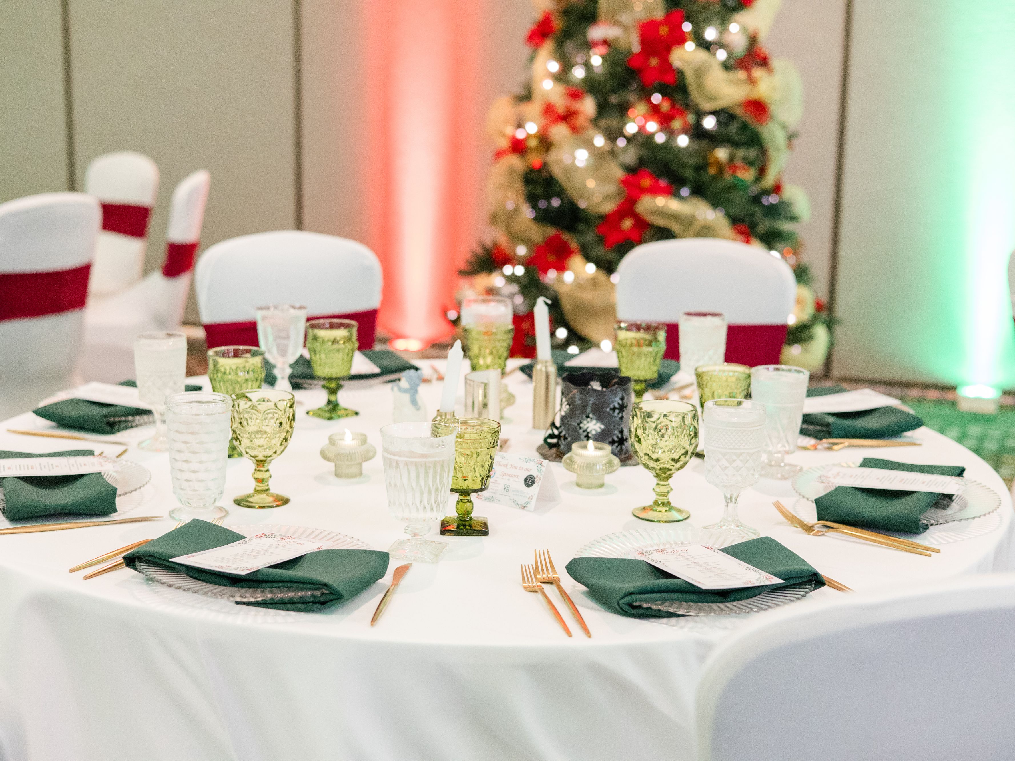 Banquet table set for holiday dinner by decorated Christmas tree