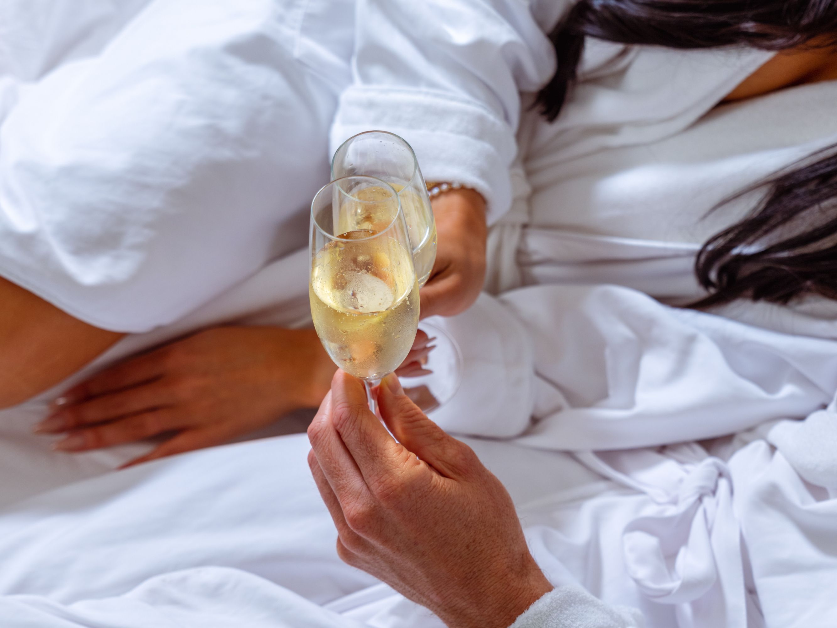 Guests enjoying champagne in hotel bed.