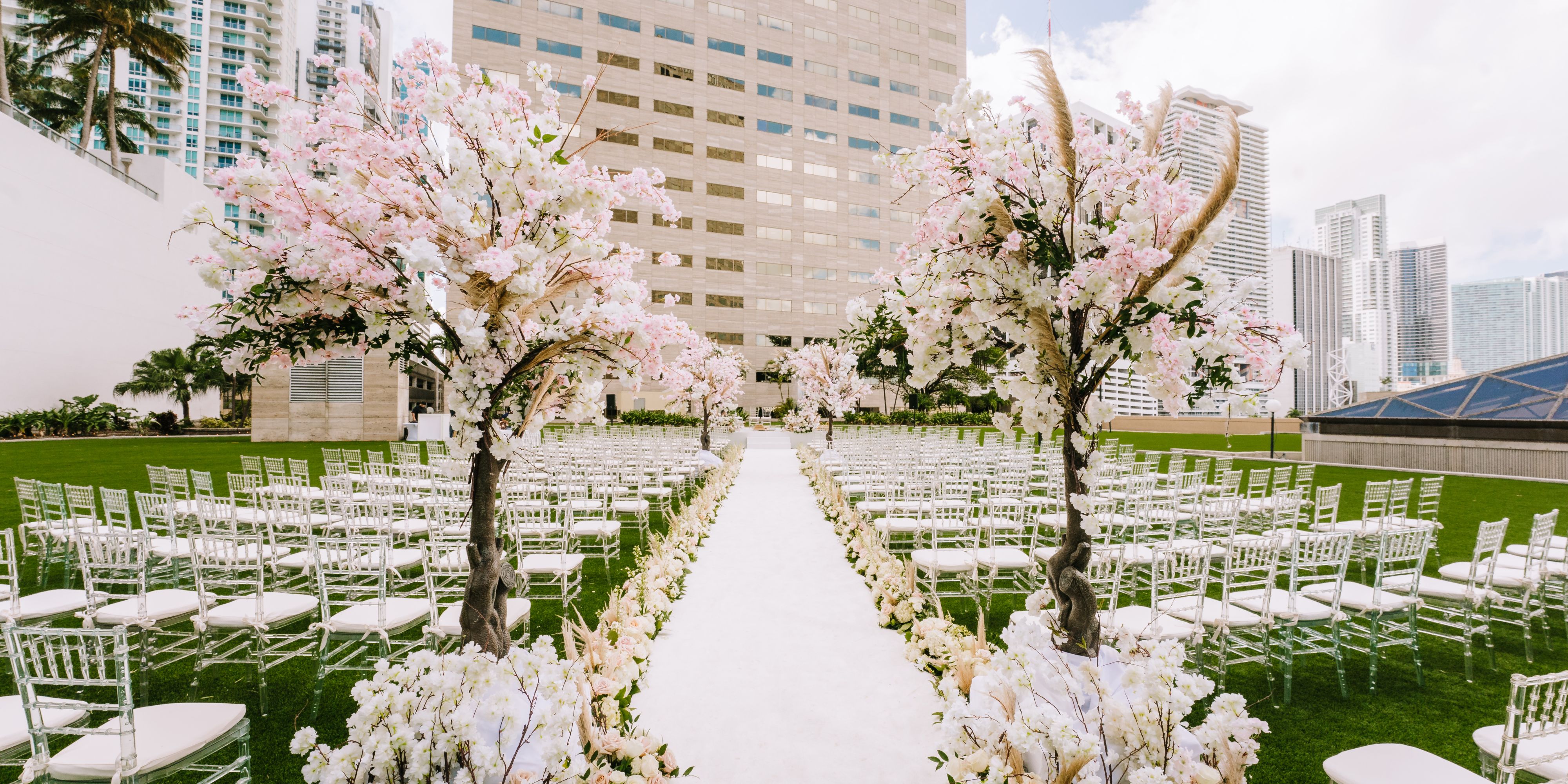 Outdoor wedding with chairs and a flower-lined aisle.