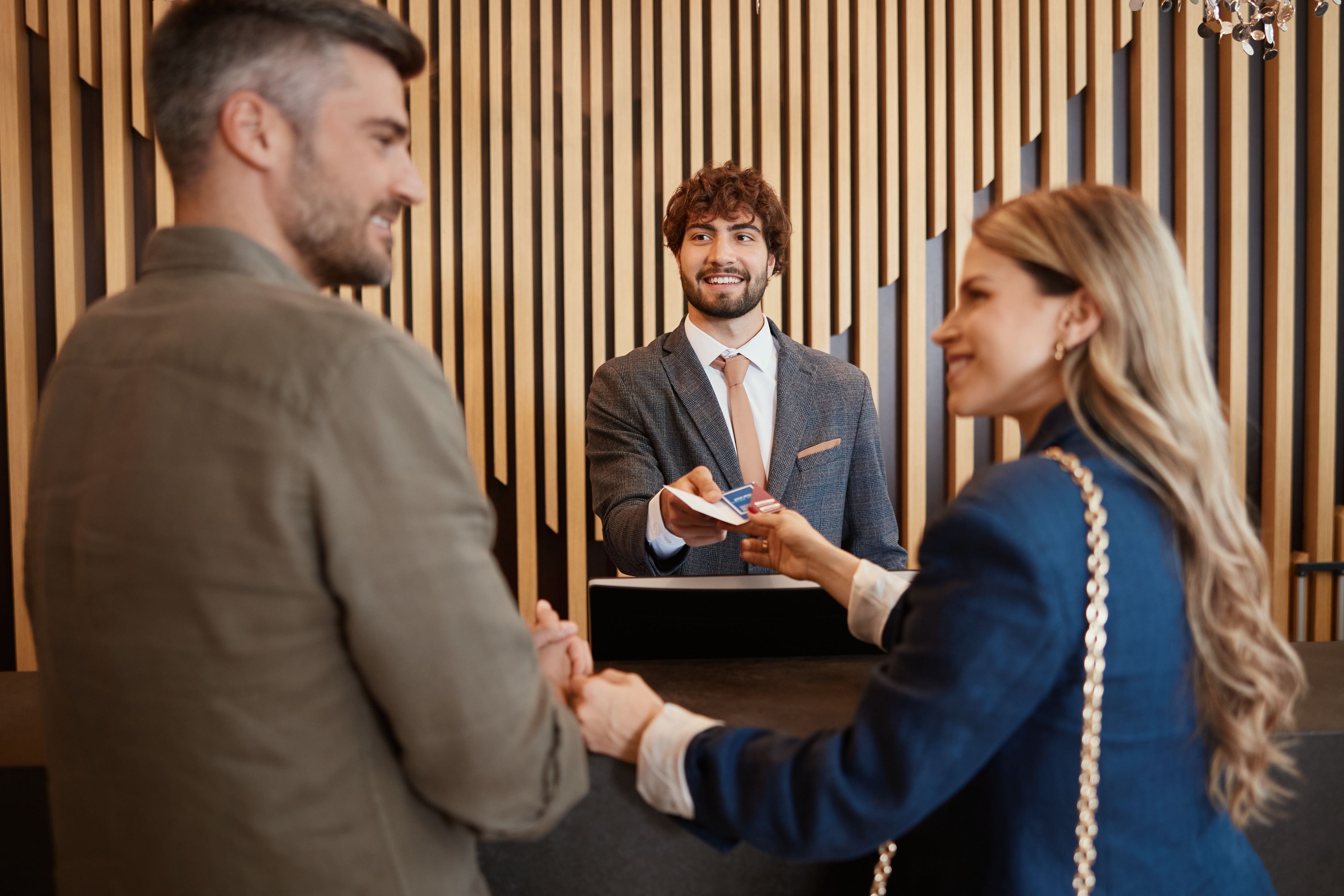 Employee welcoming two guests at the check in desk.