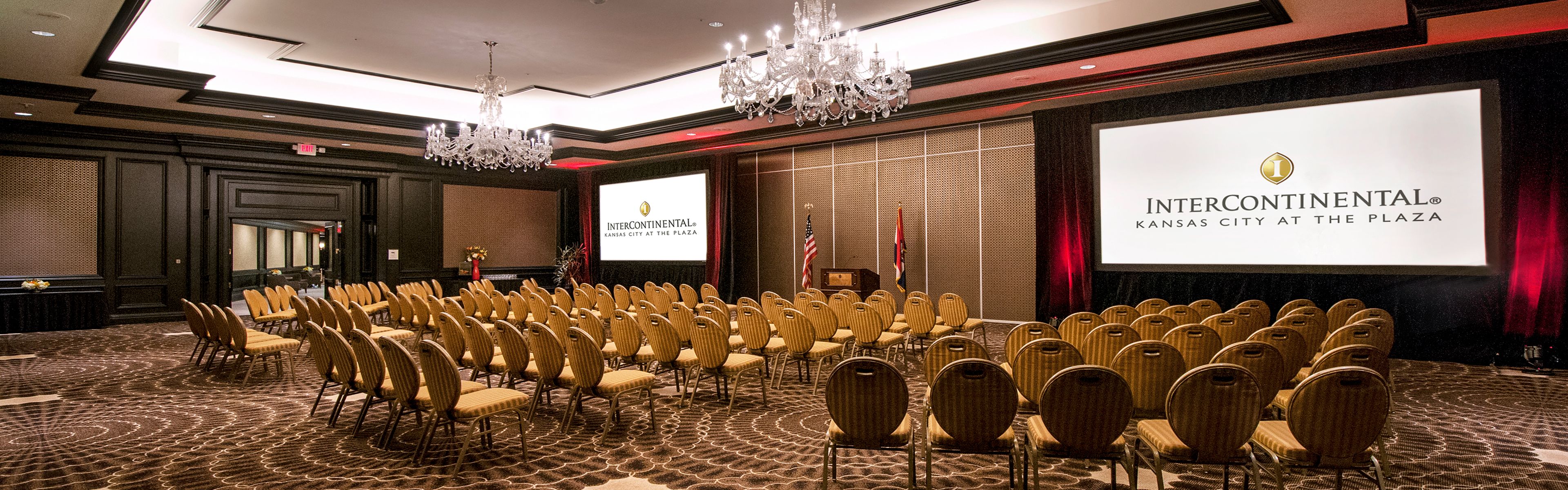 Conference room set in theater style with rows of chairs facing stage, large presentation screens displaying InterContinental Kansas City at the Plaza branding