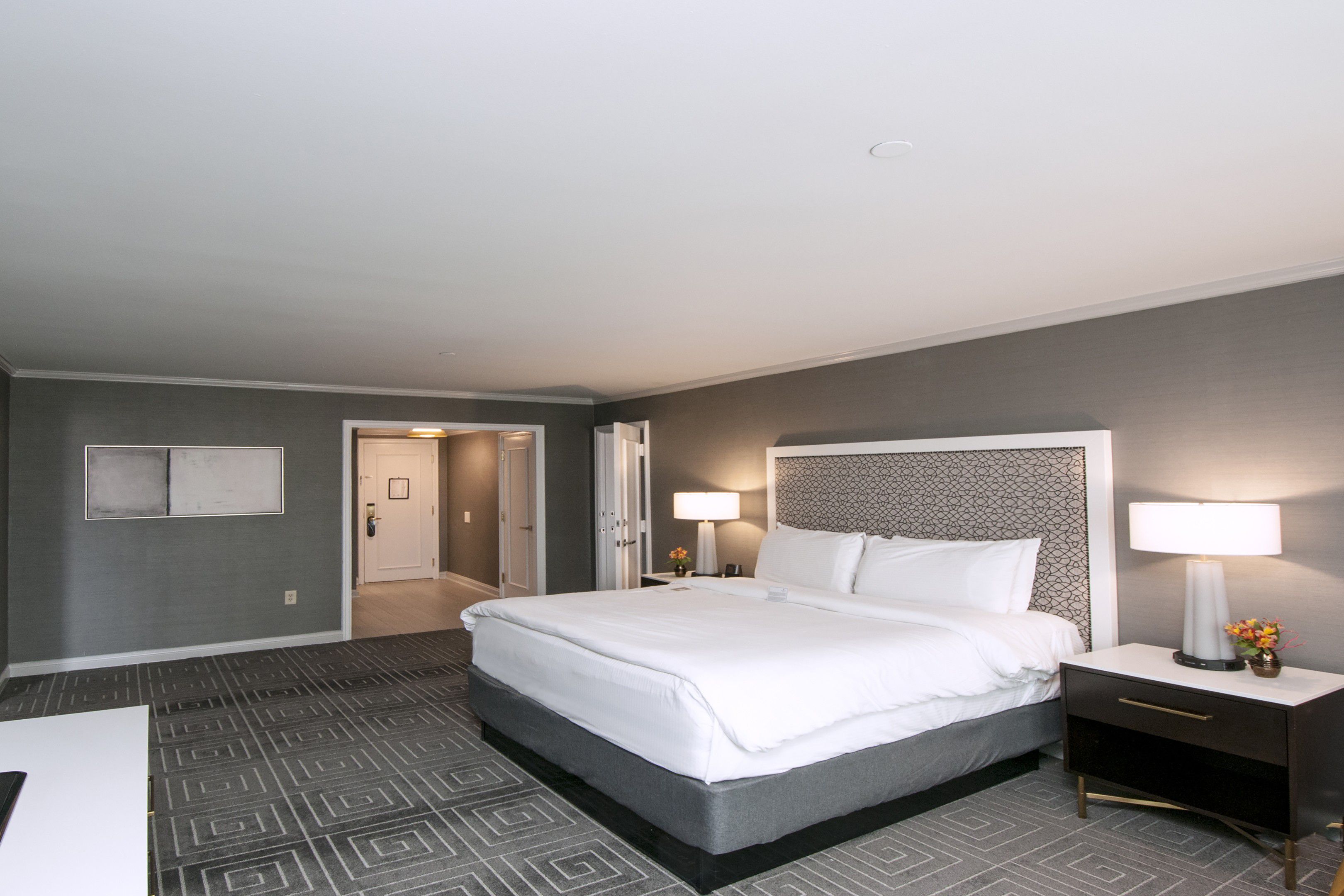 Guest room with king bed, bedside lighting, and open floor space