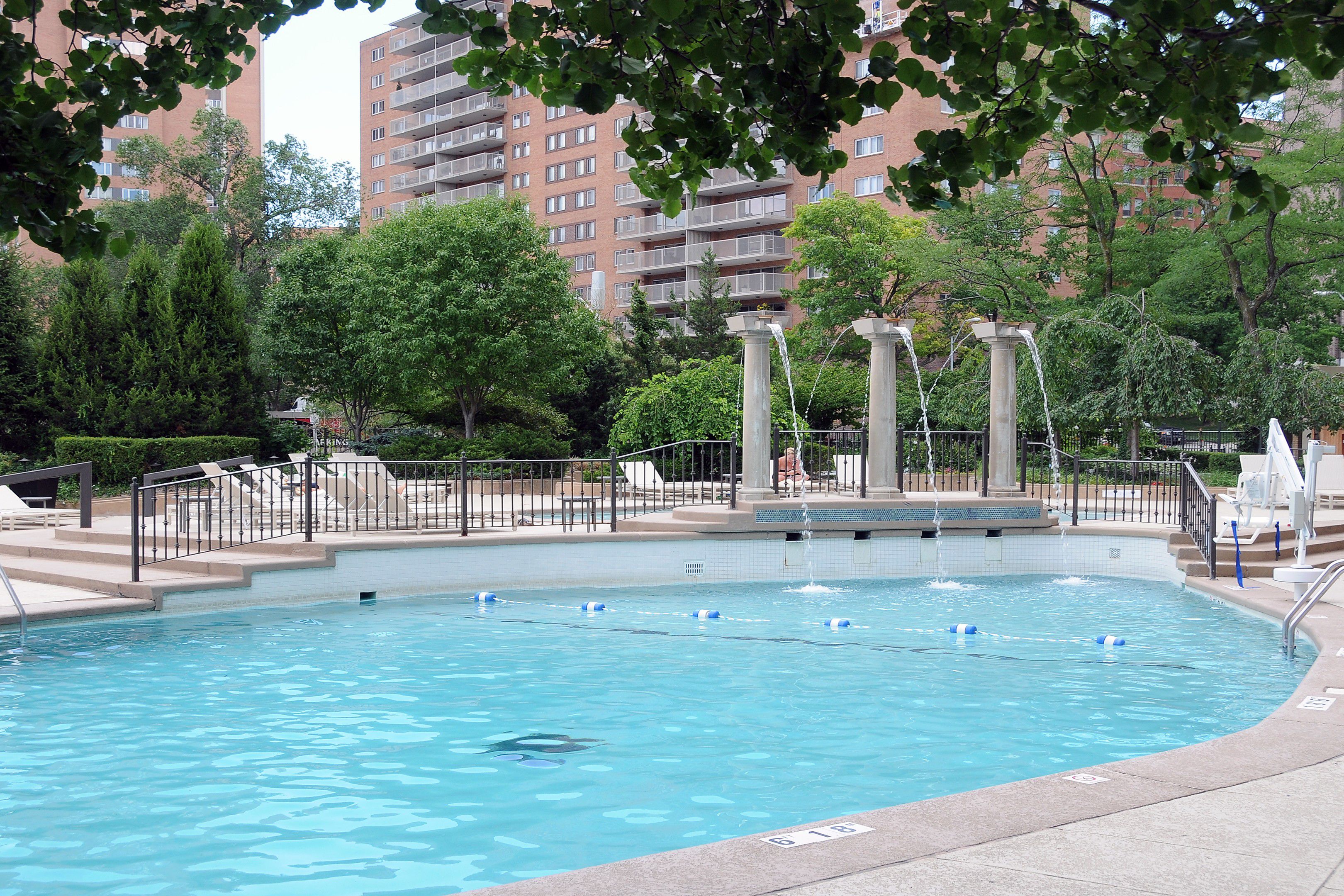 Outdoor hotel pool with surrounding deck and nearby buildings