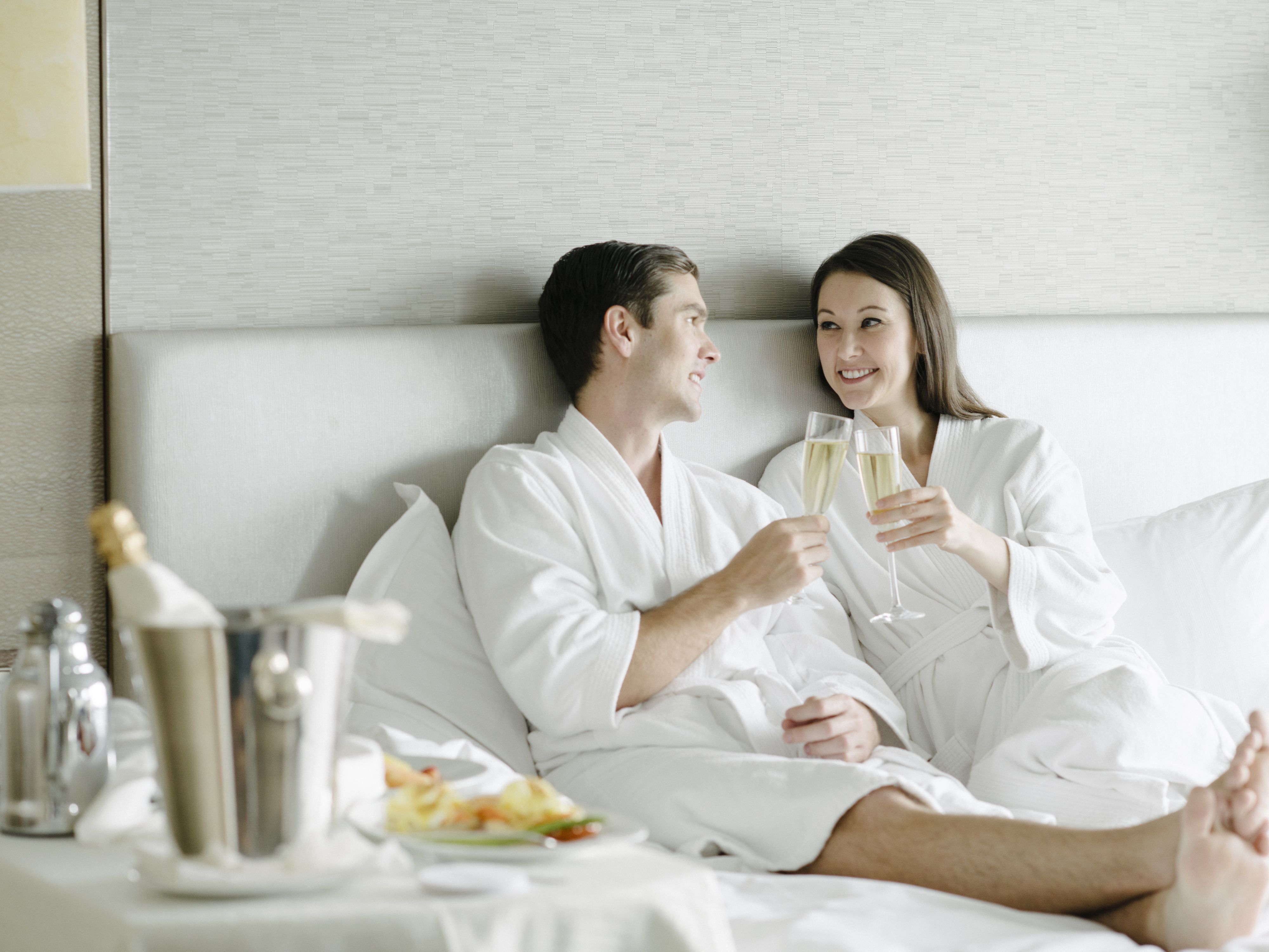 Guests in robes enjoying champagne and in-room dining