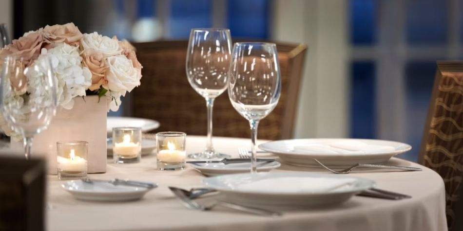 Wedding reception table set with plates, glasses, silverware, and floral centerpieces.