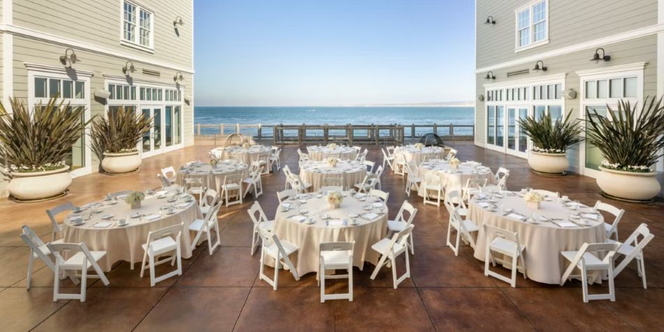 Outdoor wedding reception set up with round tables and an ocean view.