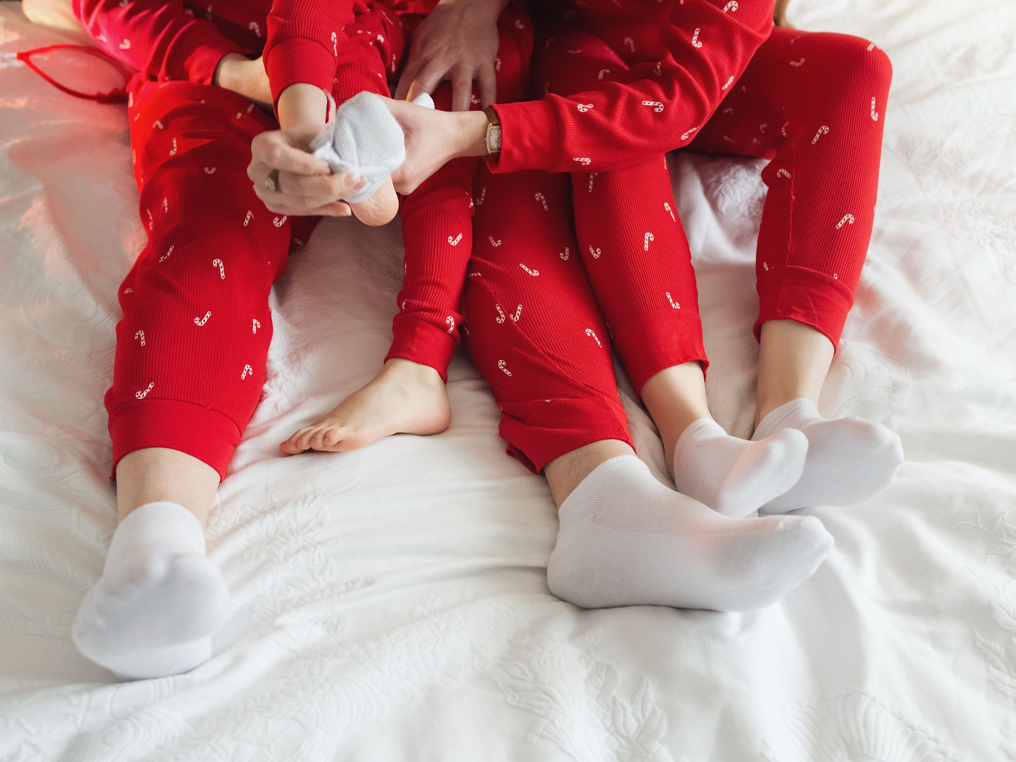 family in Christmas pajamas on bed