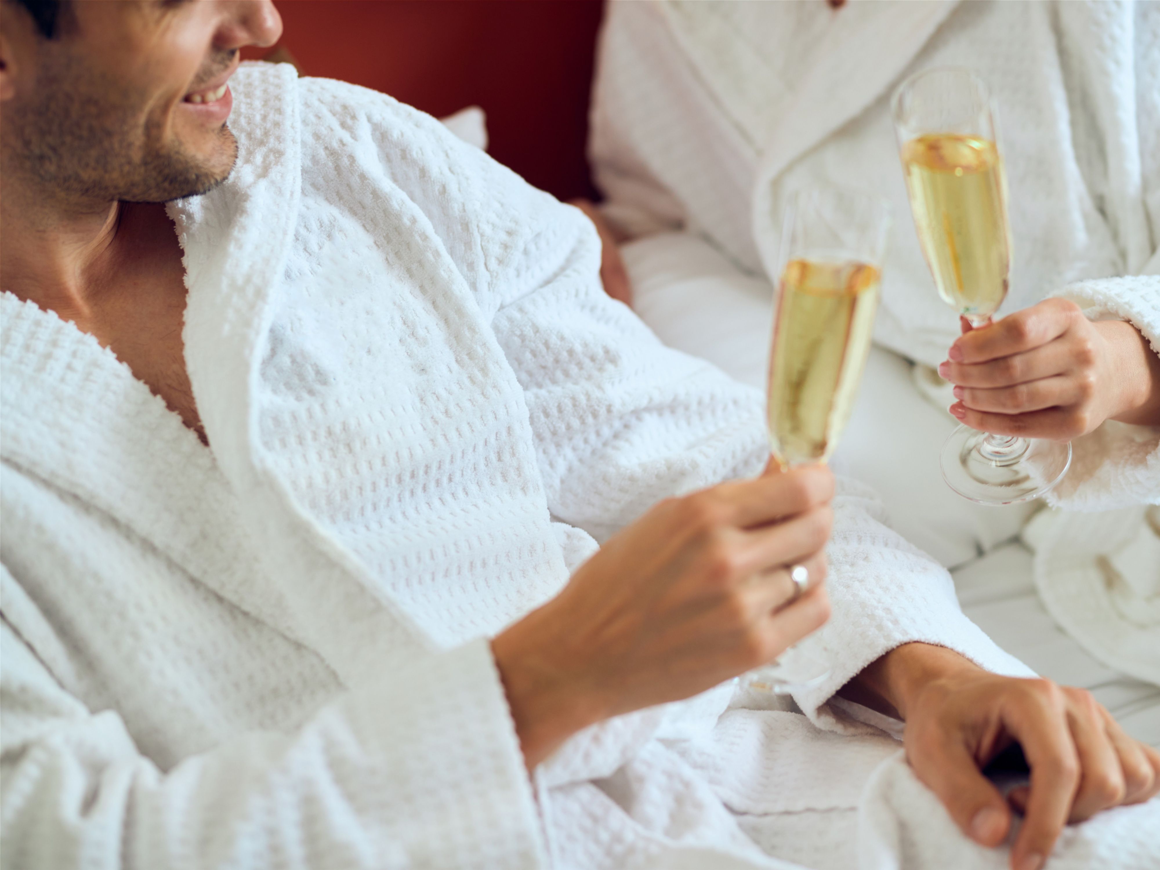 couple holding champagne glasses in robes
