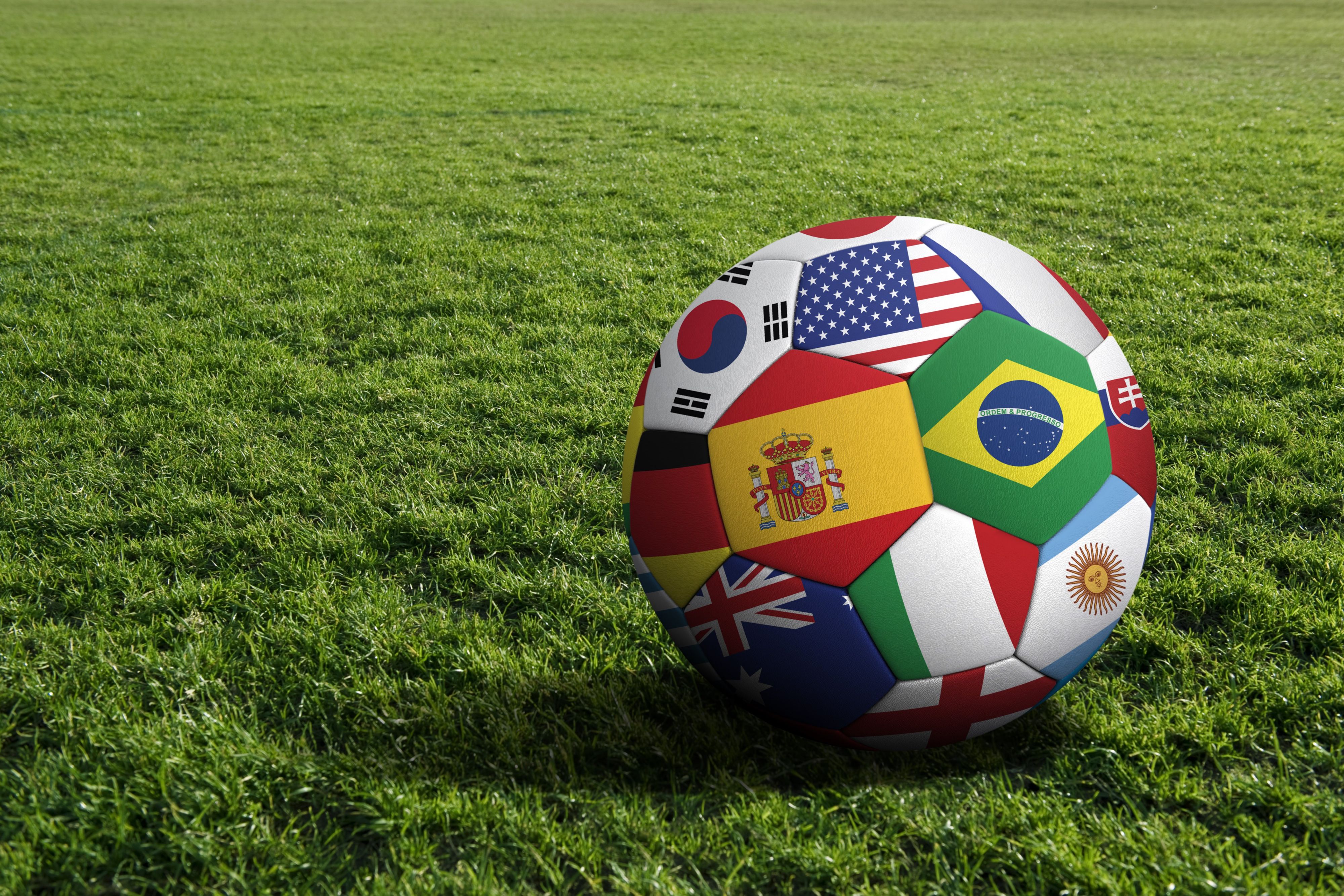 Soccer ball with international country flags on a grass field