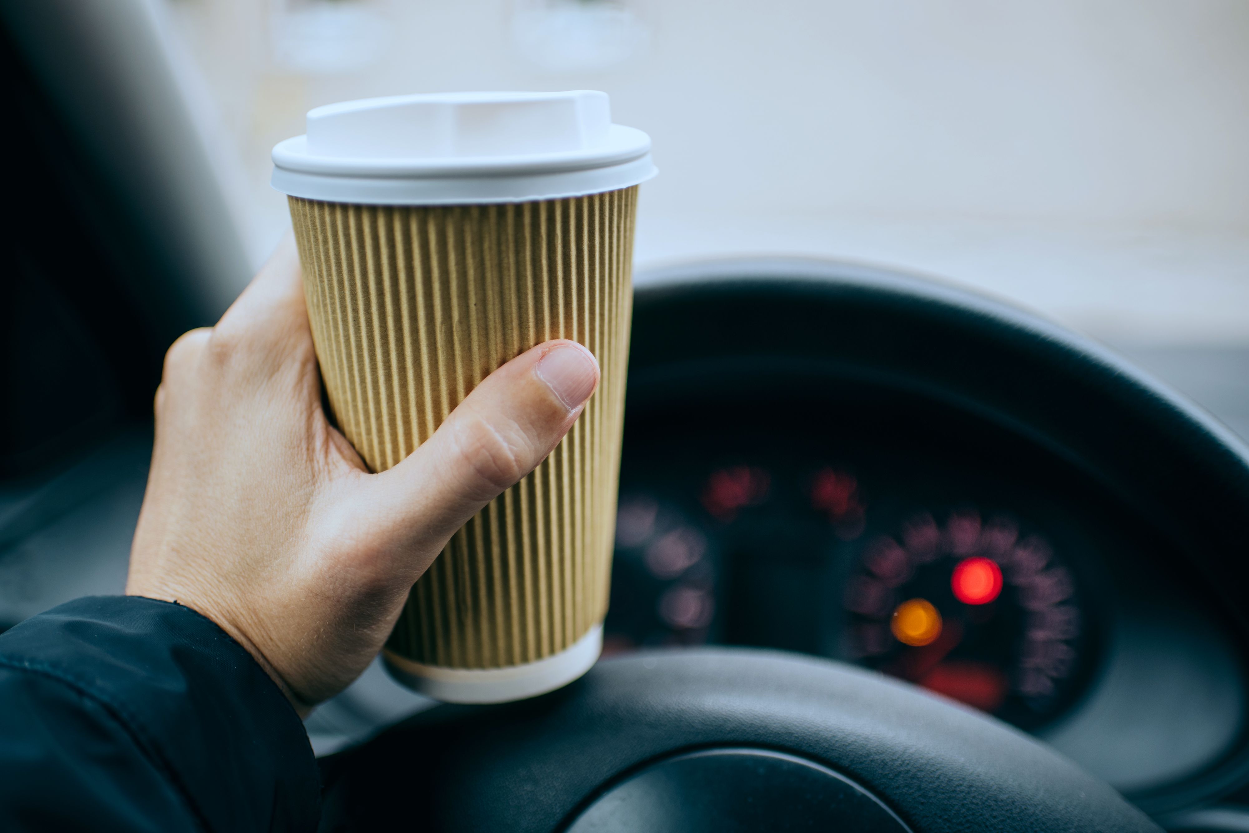 person driving with coffee in hand