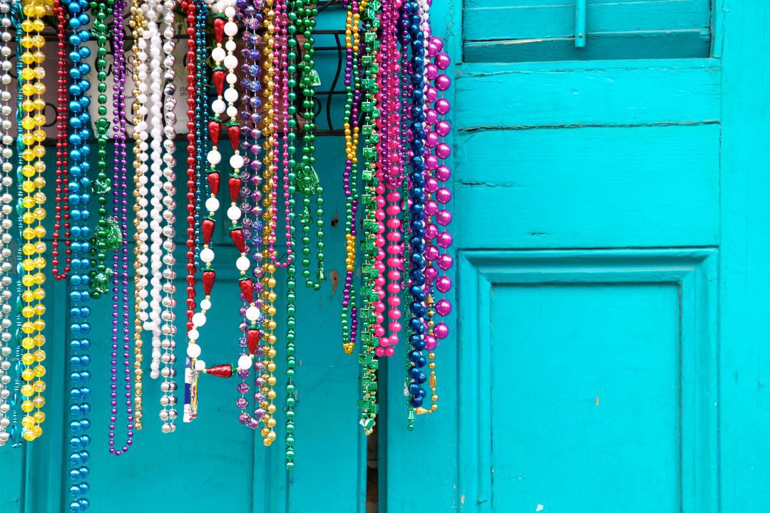 Photo of Mardo Gras beads hanging in front of turquoise door