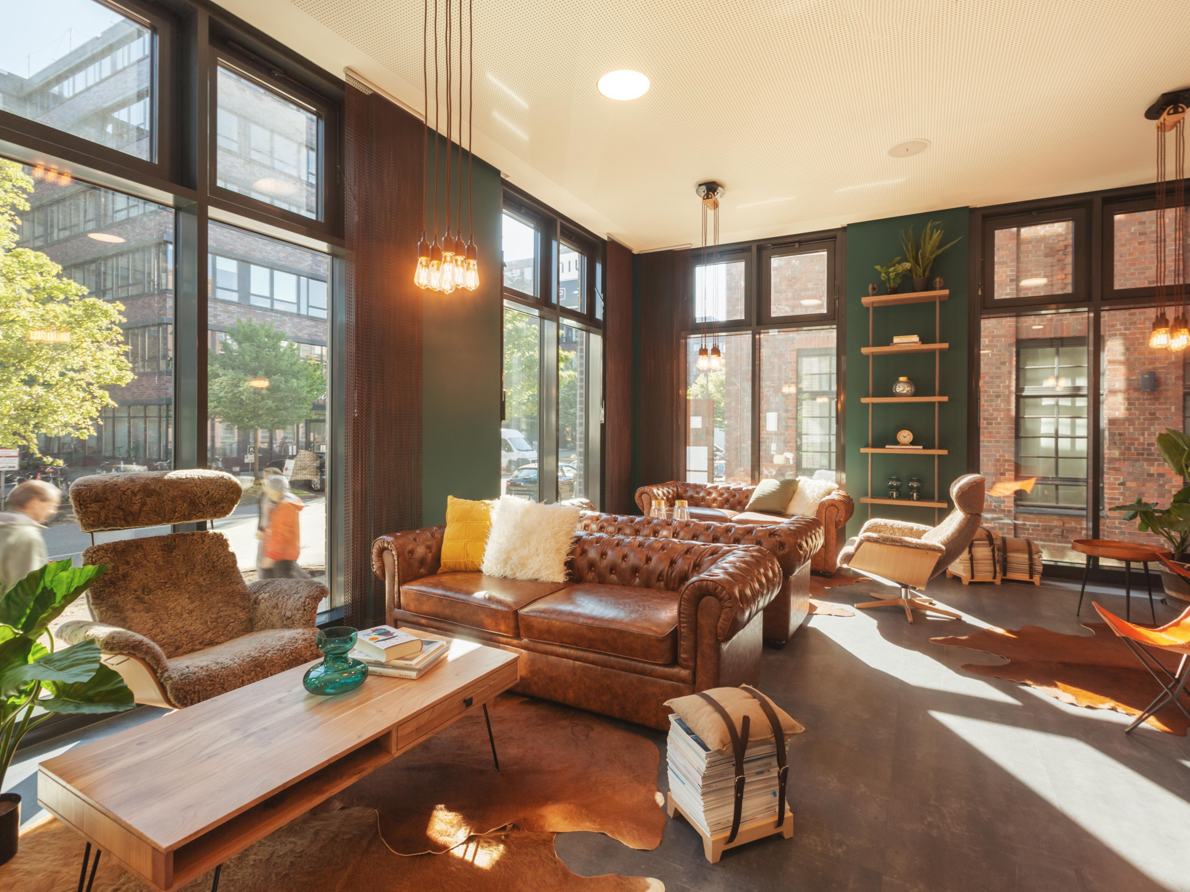 Industrial chic combined with inviting coziness. Exposed brick walls, leather, metal, and wood create an urban vibe. In the spacious living room lobby with leather sofas and flexible poufs, guests gather to relax or work. The eclectic style mix, enhanced by Björn Holzweg’s nature impressions, is truly inspiring!
