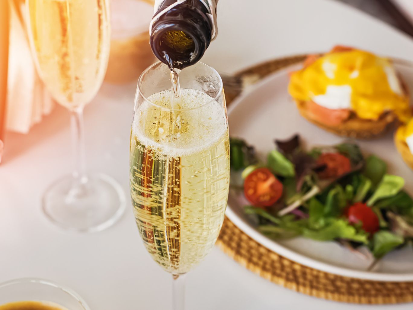 Glass of champagne with eggs benedict and small salad