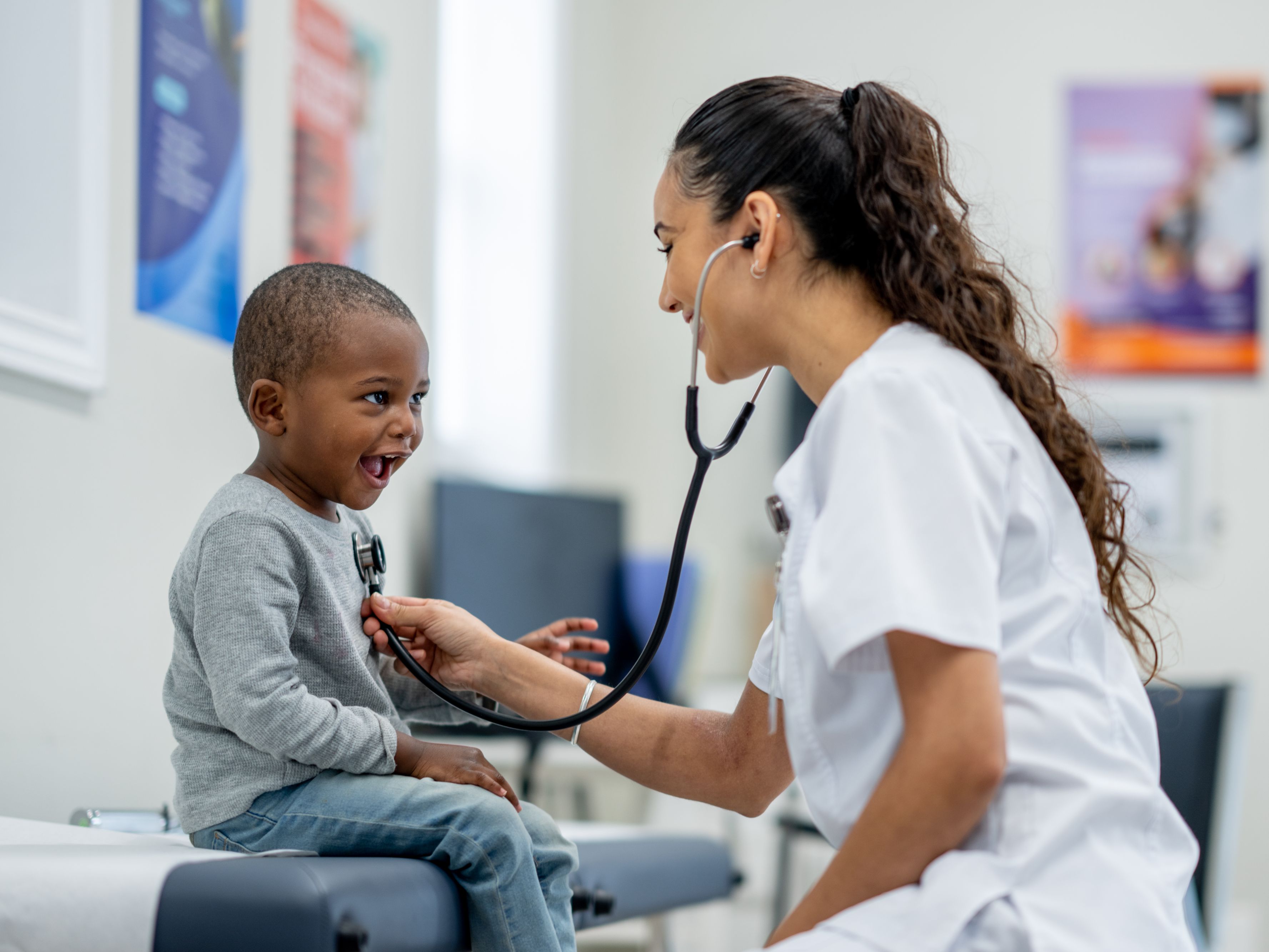 Nurse checking a smiling child's heartbeat at the hospital.