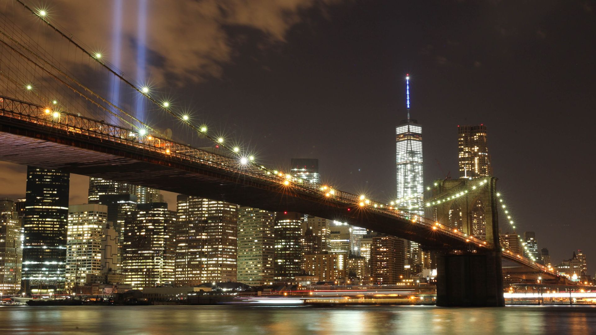 nighttime view of the brooklyn bridge overlooking new york city skyline