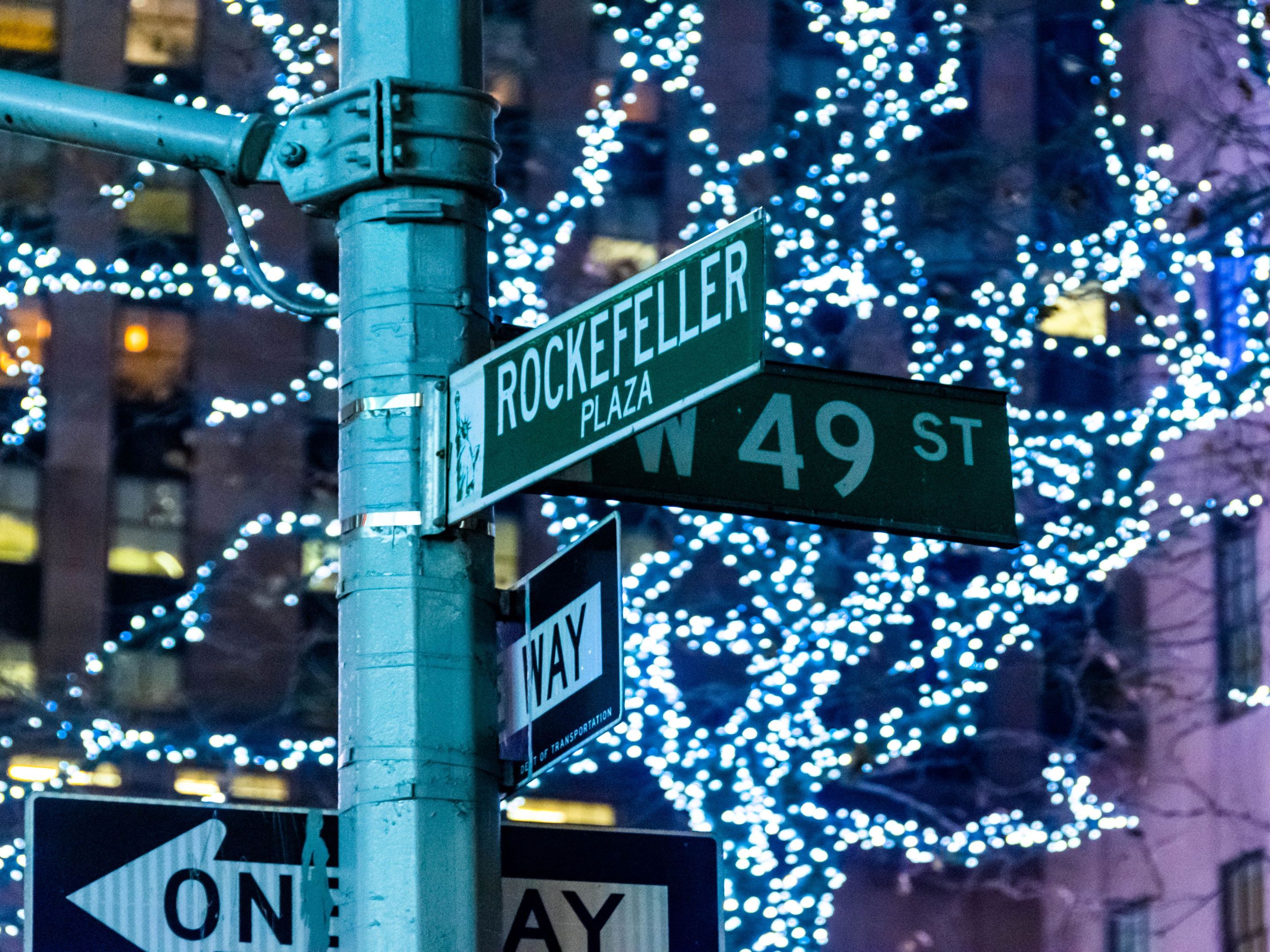 NYC street signs with Christmas lights in background.