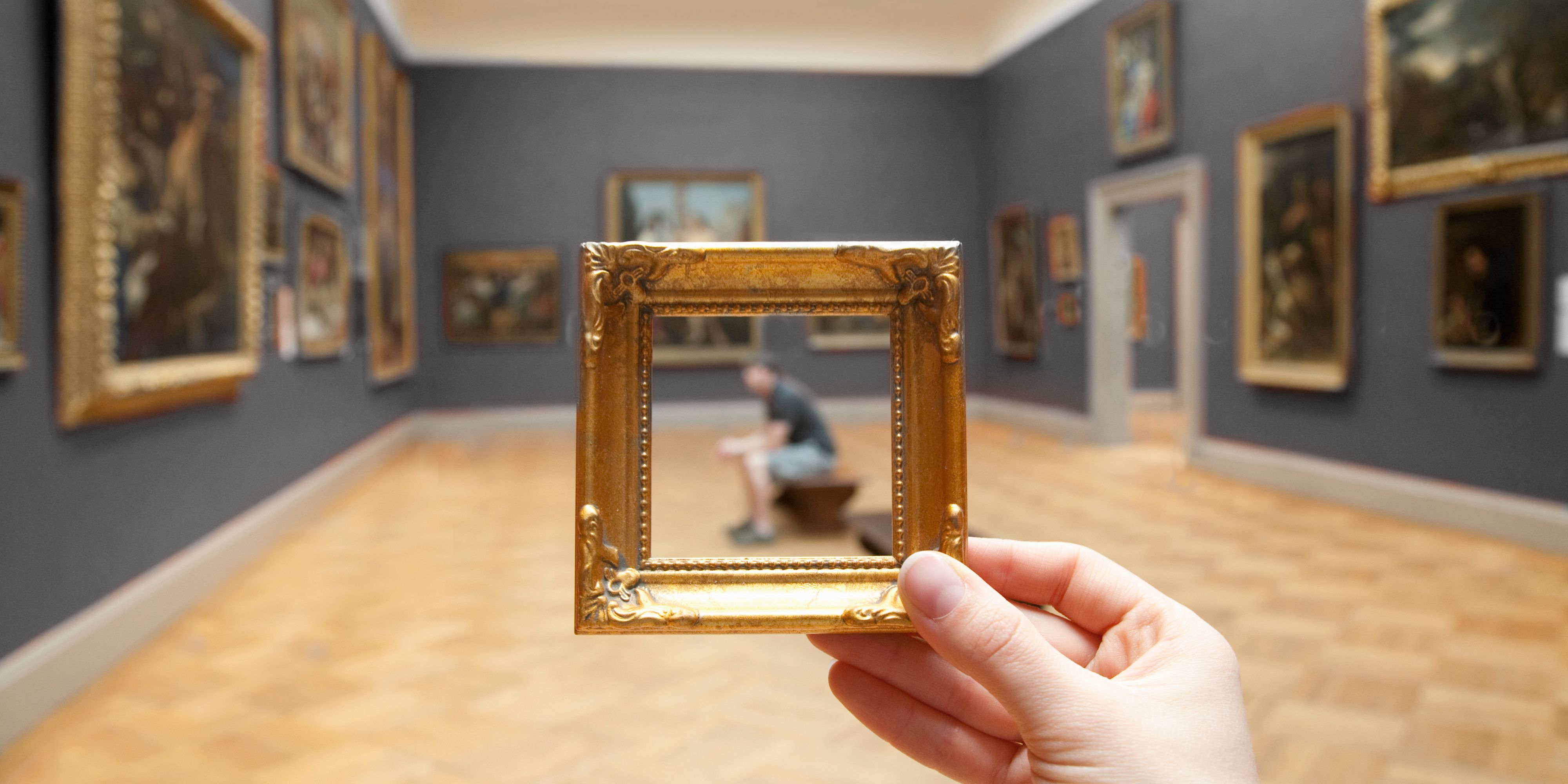 Person holding up a frame around a guest at a museum