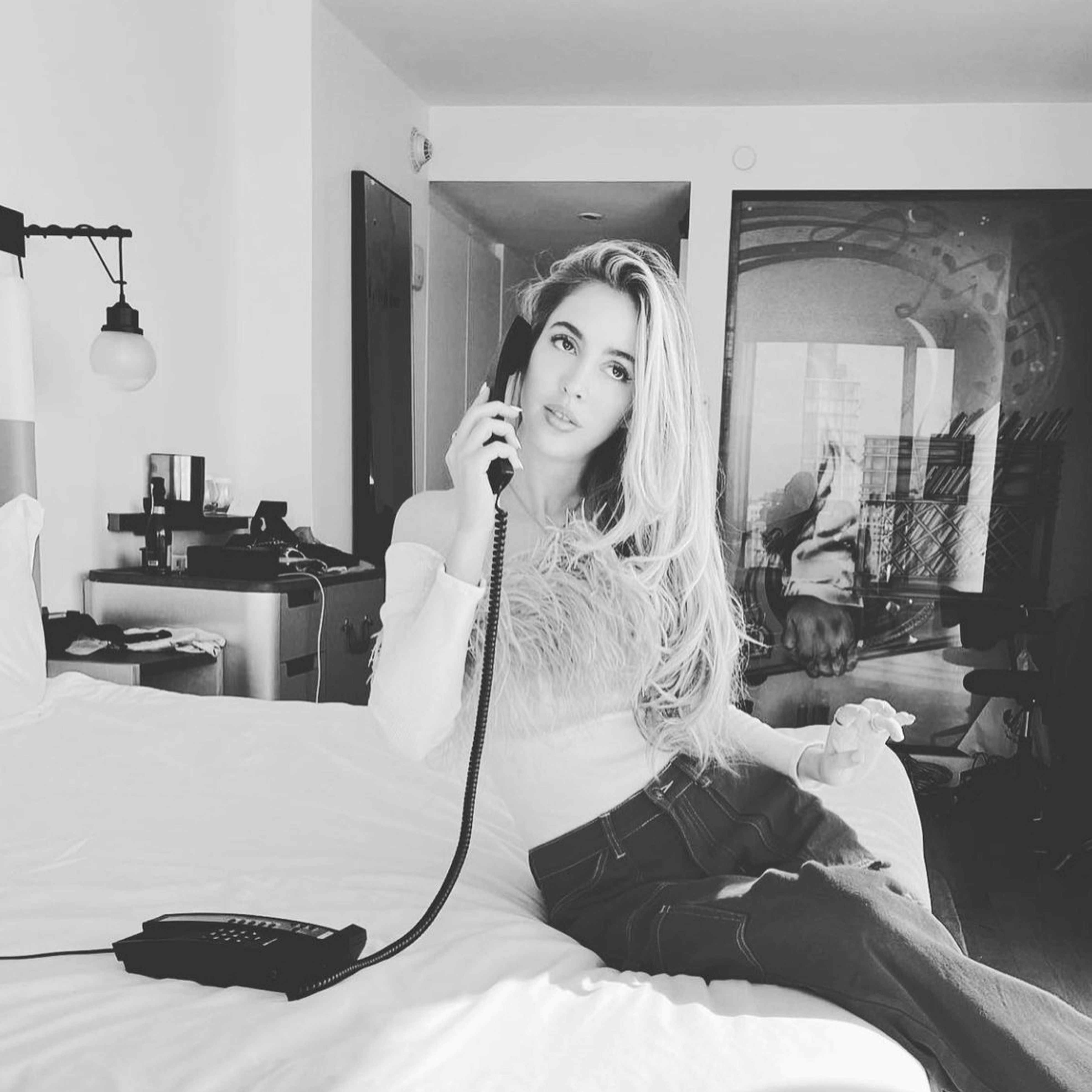 Woman posing on King bed with hotel phone