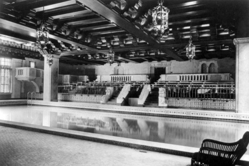 Historic indoor swimming pool with ornate architecture and hanging lanterns