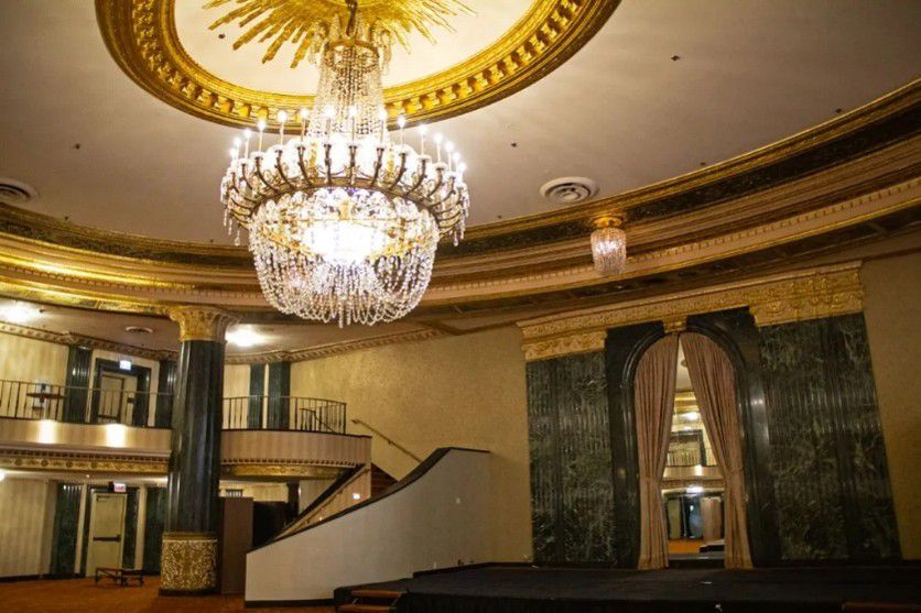 Grand ballroom with crystal chandelier, marble columns, and stage