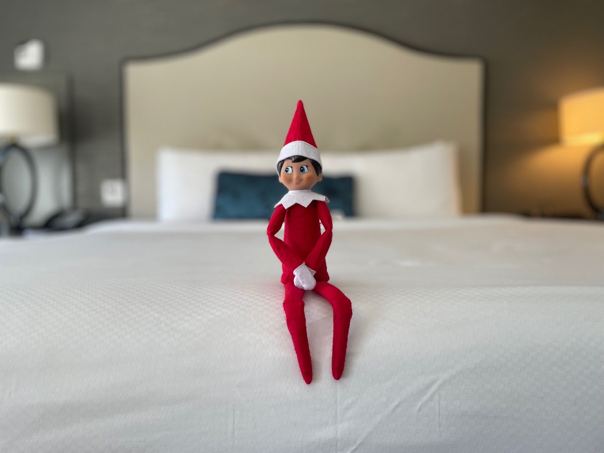 Elf on a shelf sitting on hotel bed