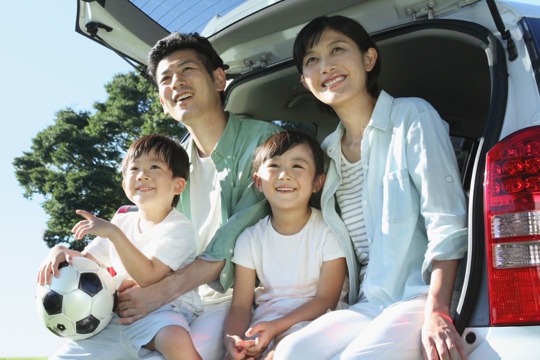family sitting in back on suv holding soccer ball