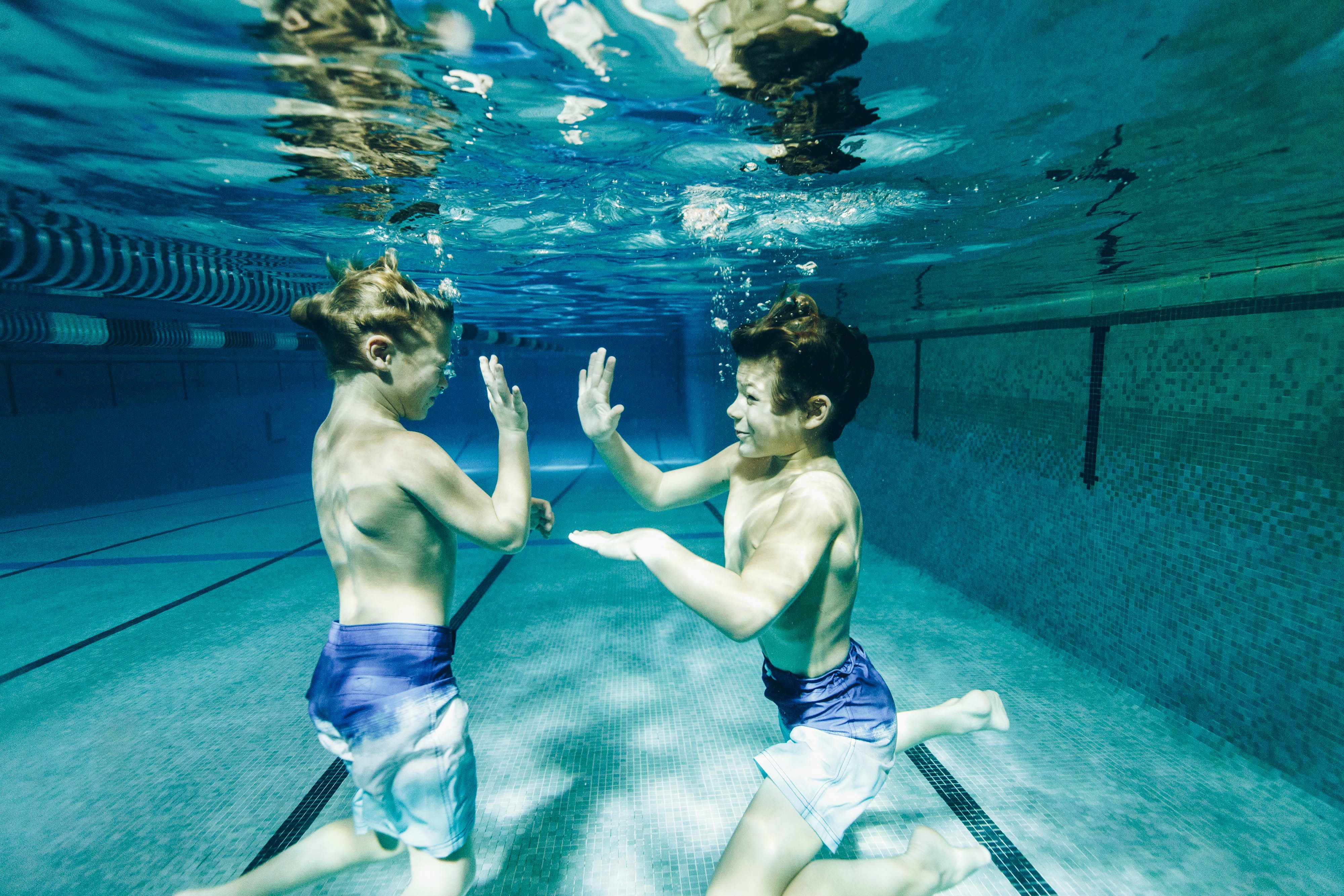 Children playing underwater in an indoor swimming pool.