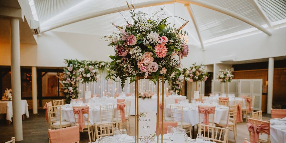 wedding seating area with pink flowers and empty tables and chairs