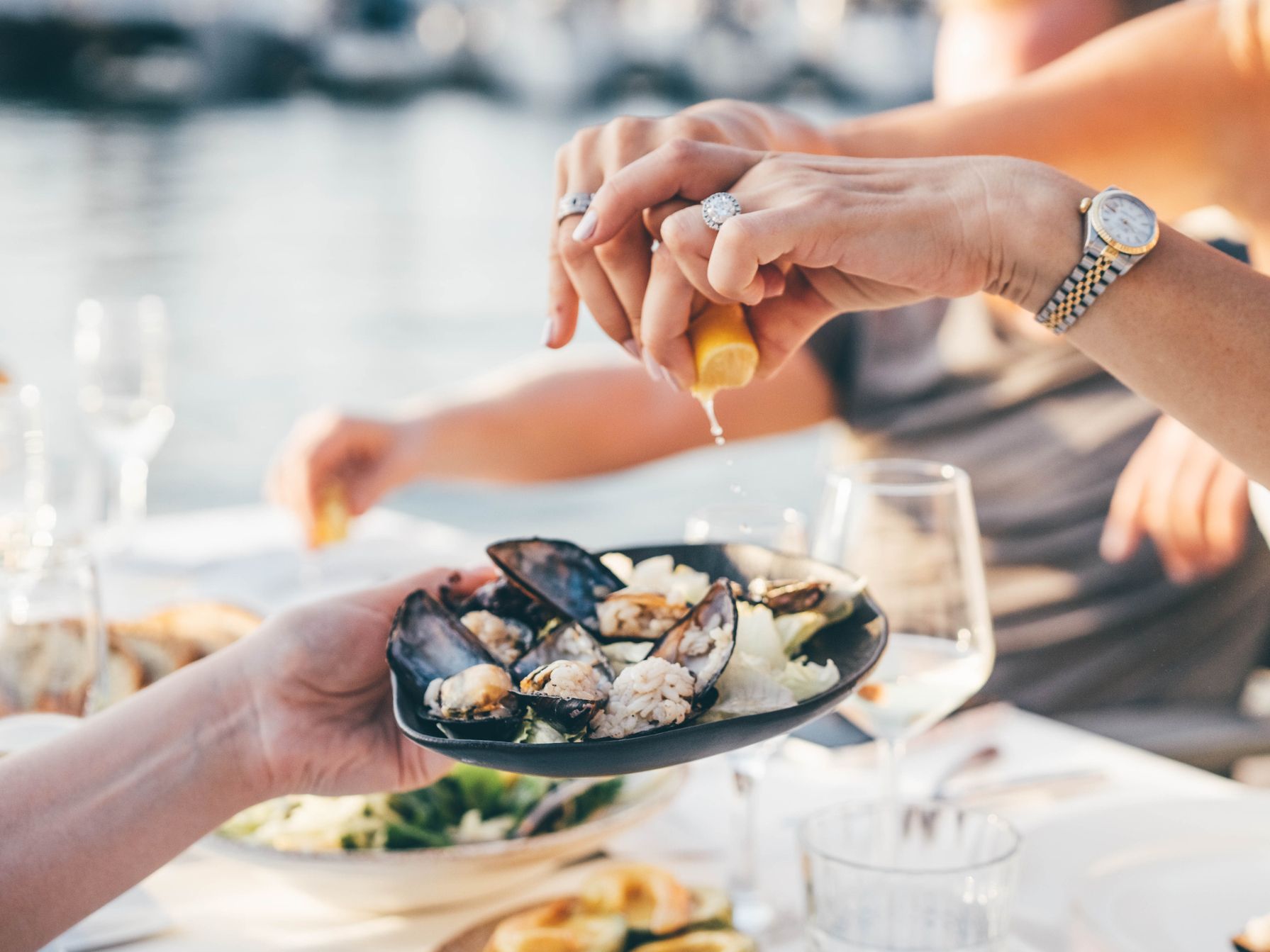 Having oysters at a restaurant with water in the background