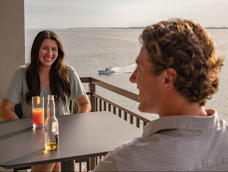 Woman and man with drinks overlooking the water