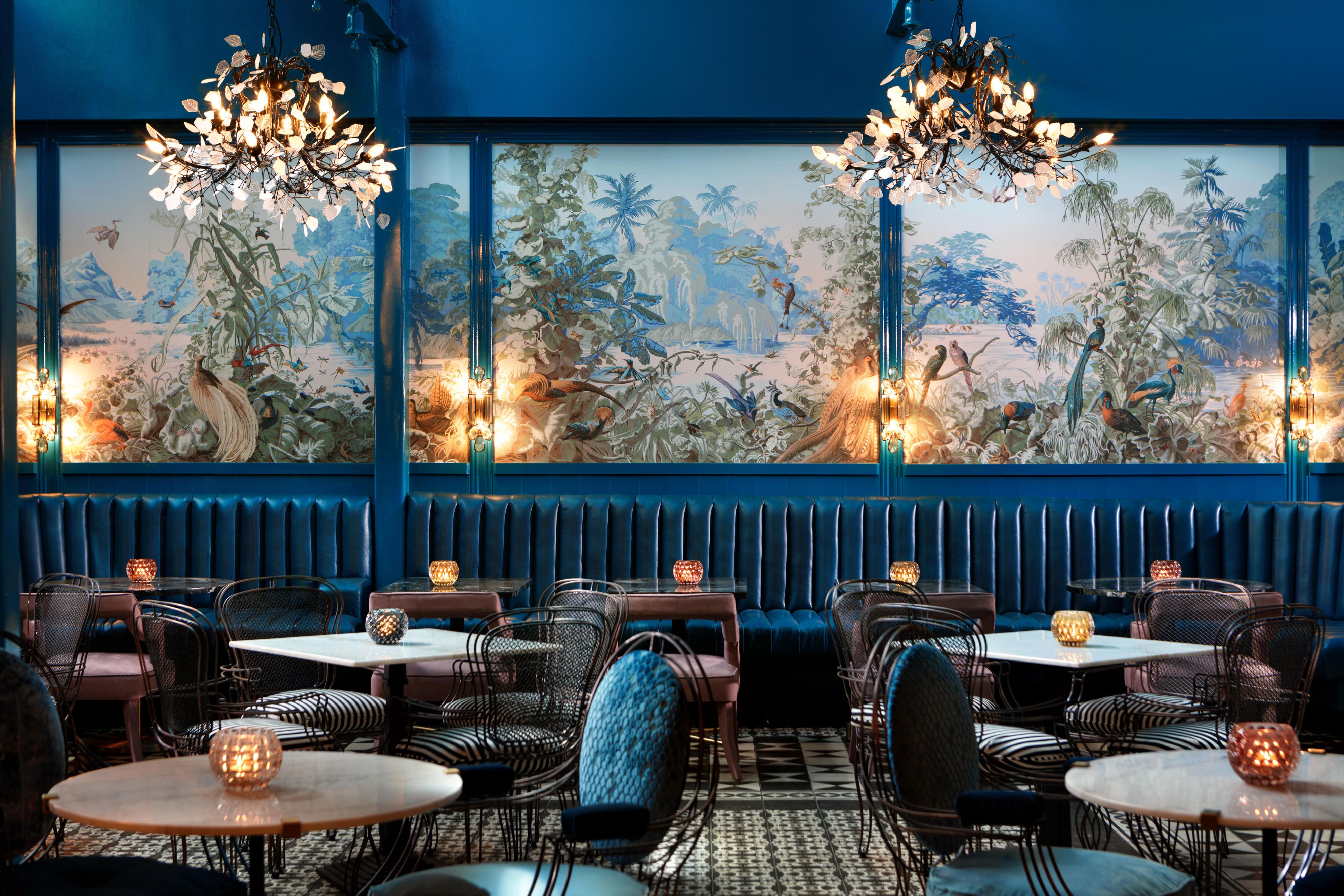dining room at peackock room with blue plush seating and colorful wall mural