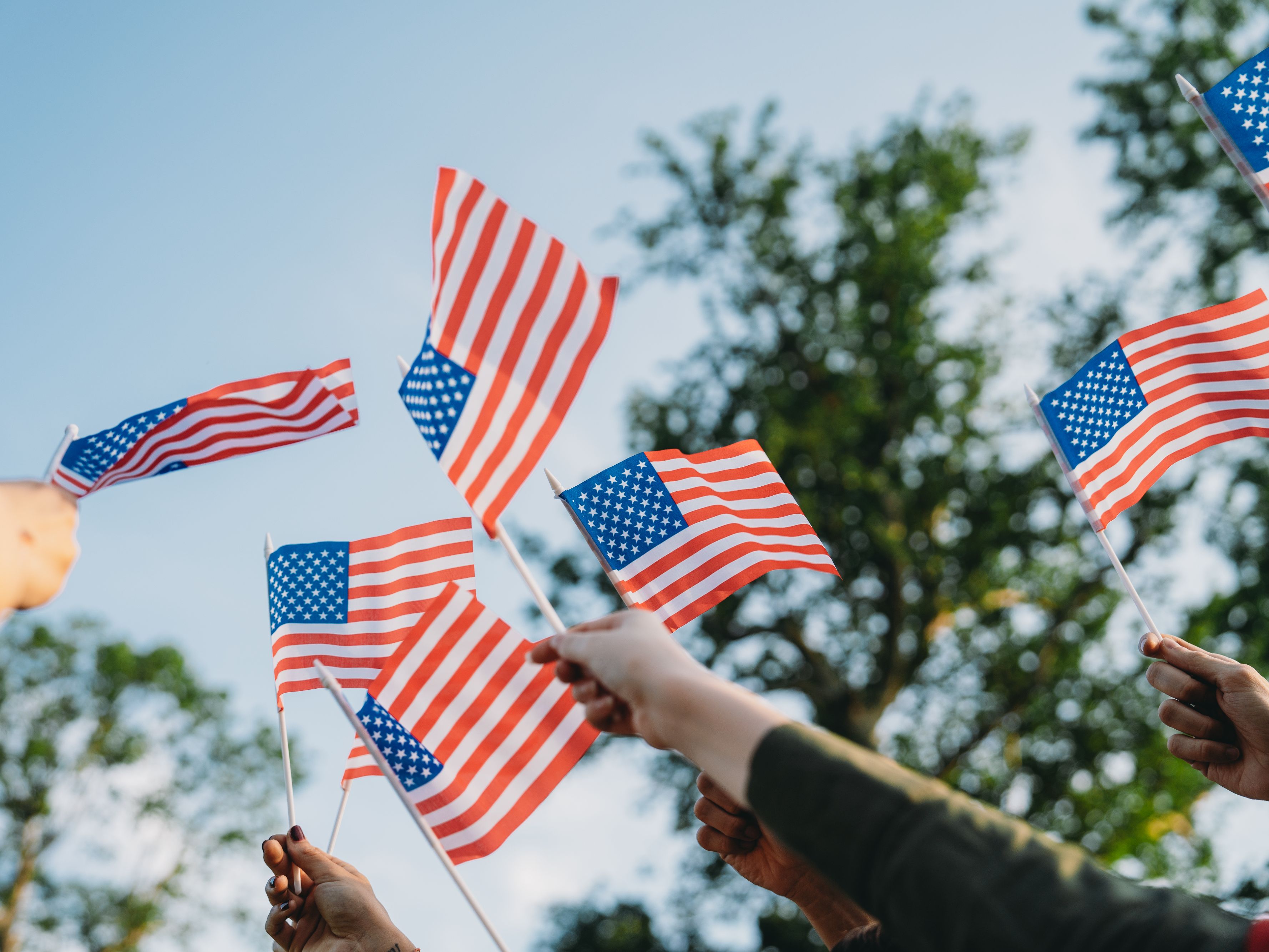 Close up of people waving mini American flags in the air.