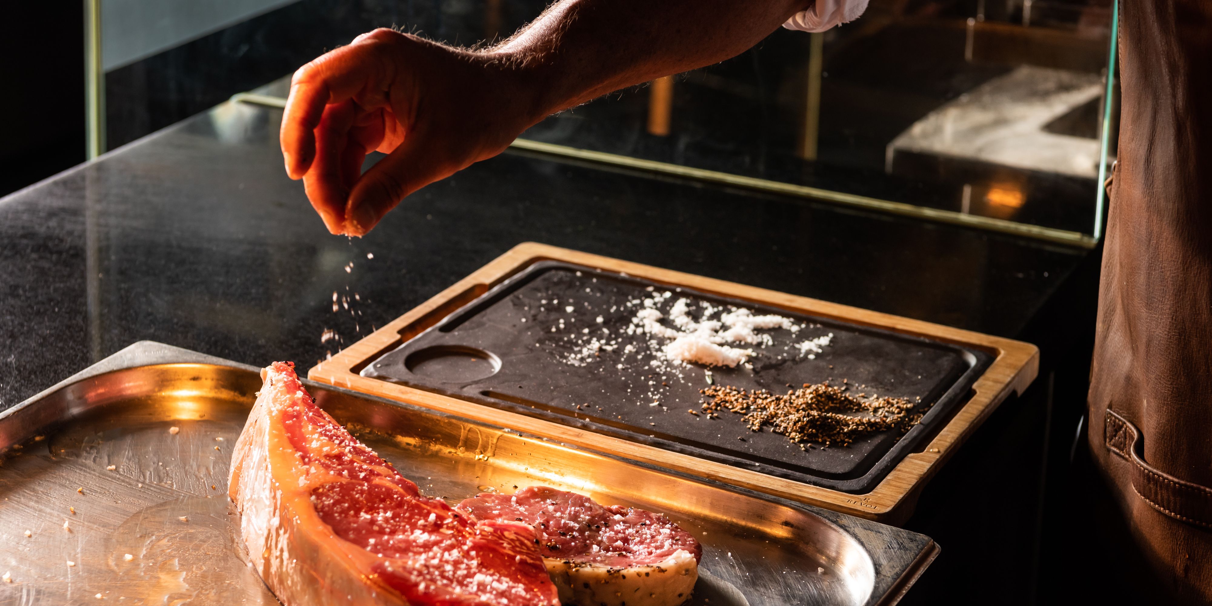 chef seasoning a steak