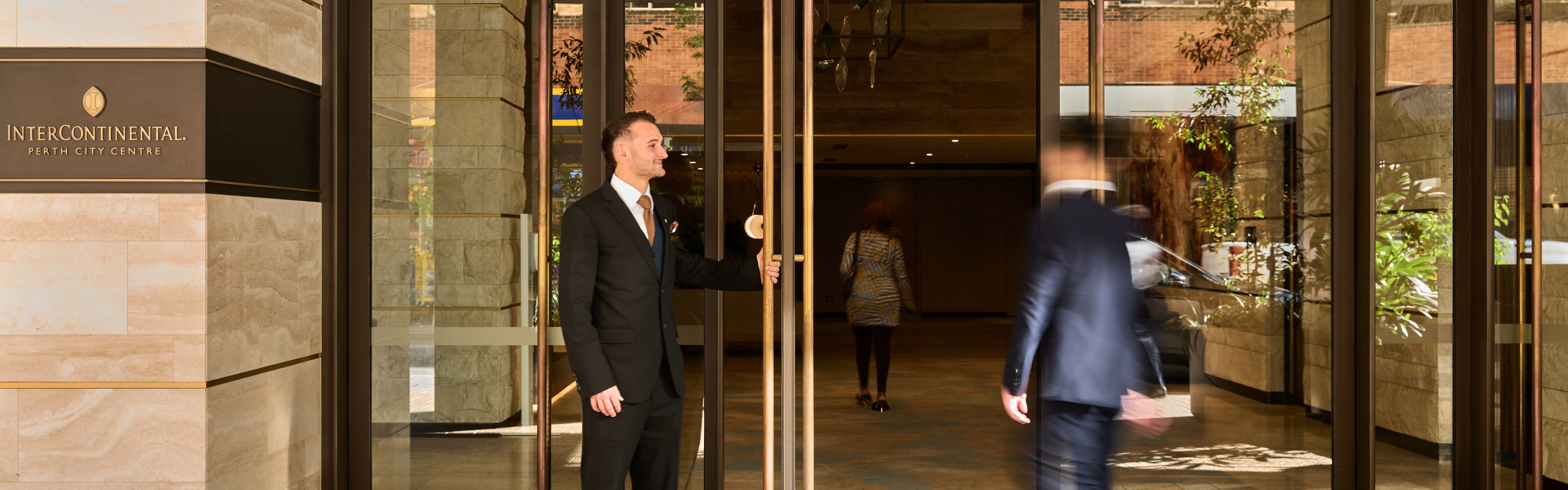 Doorman holding the door open for a guest, welcoming him to InterContinental Perth City Centre.