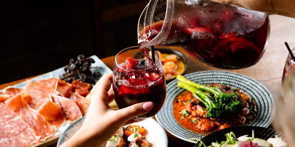 Sangria being poured from a pitcher, surrounded by dishes from IC Perth's restaurant.