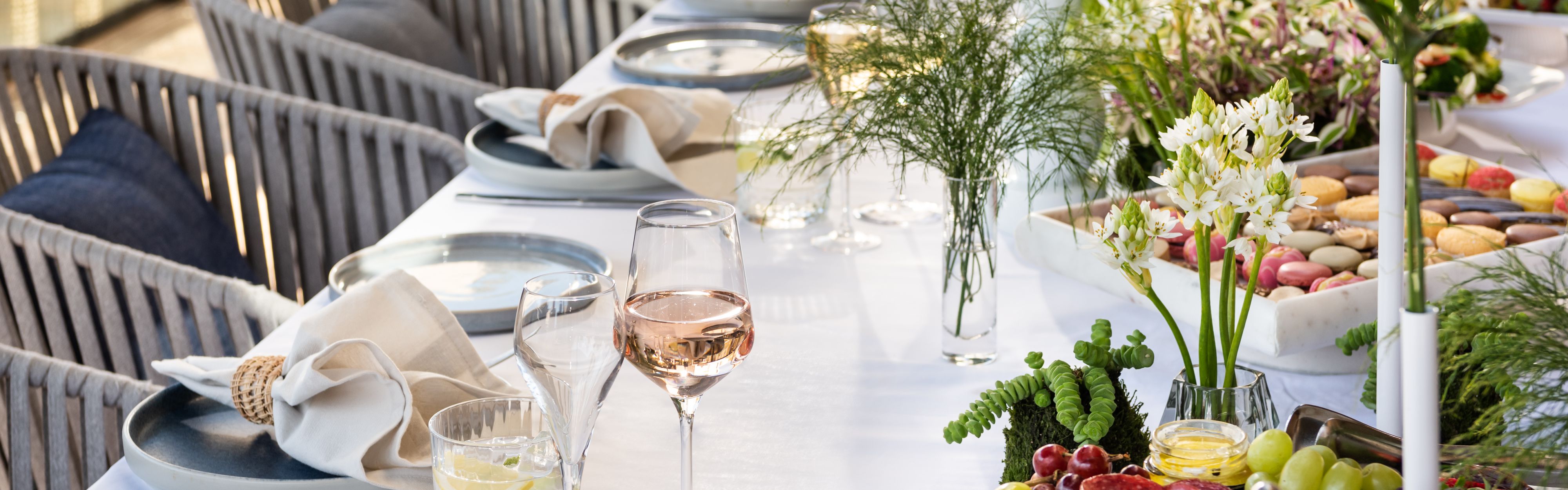 Elegant summer table set with rosé, macarons and fresh flowers.