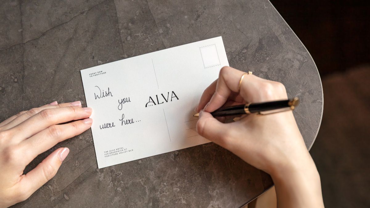 Woman writing a message on postcard.