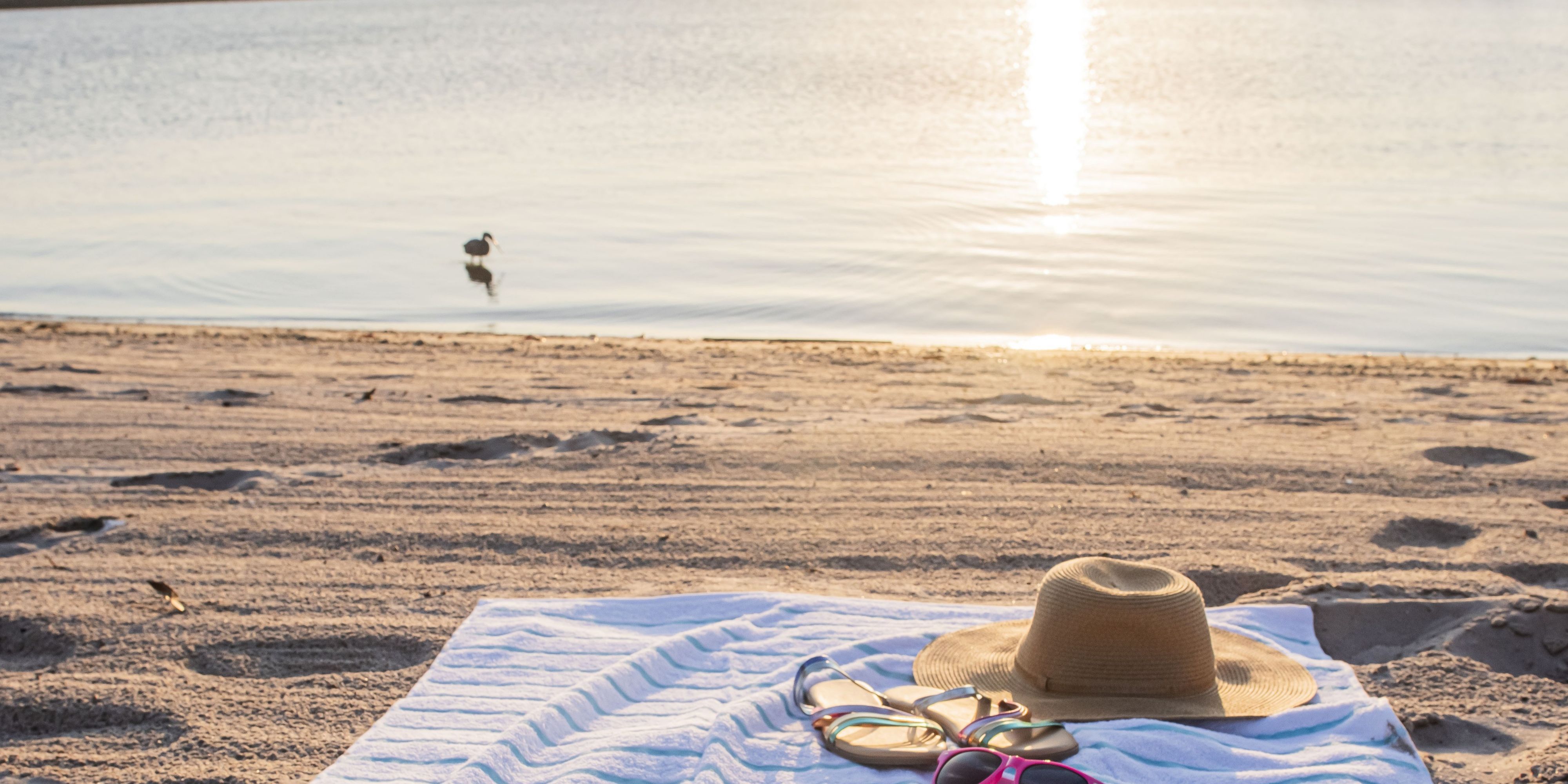 Beach towel setting, sunglases and a hat