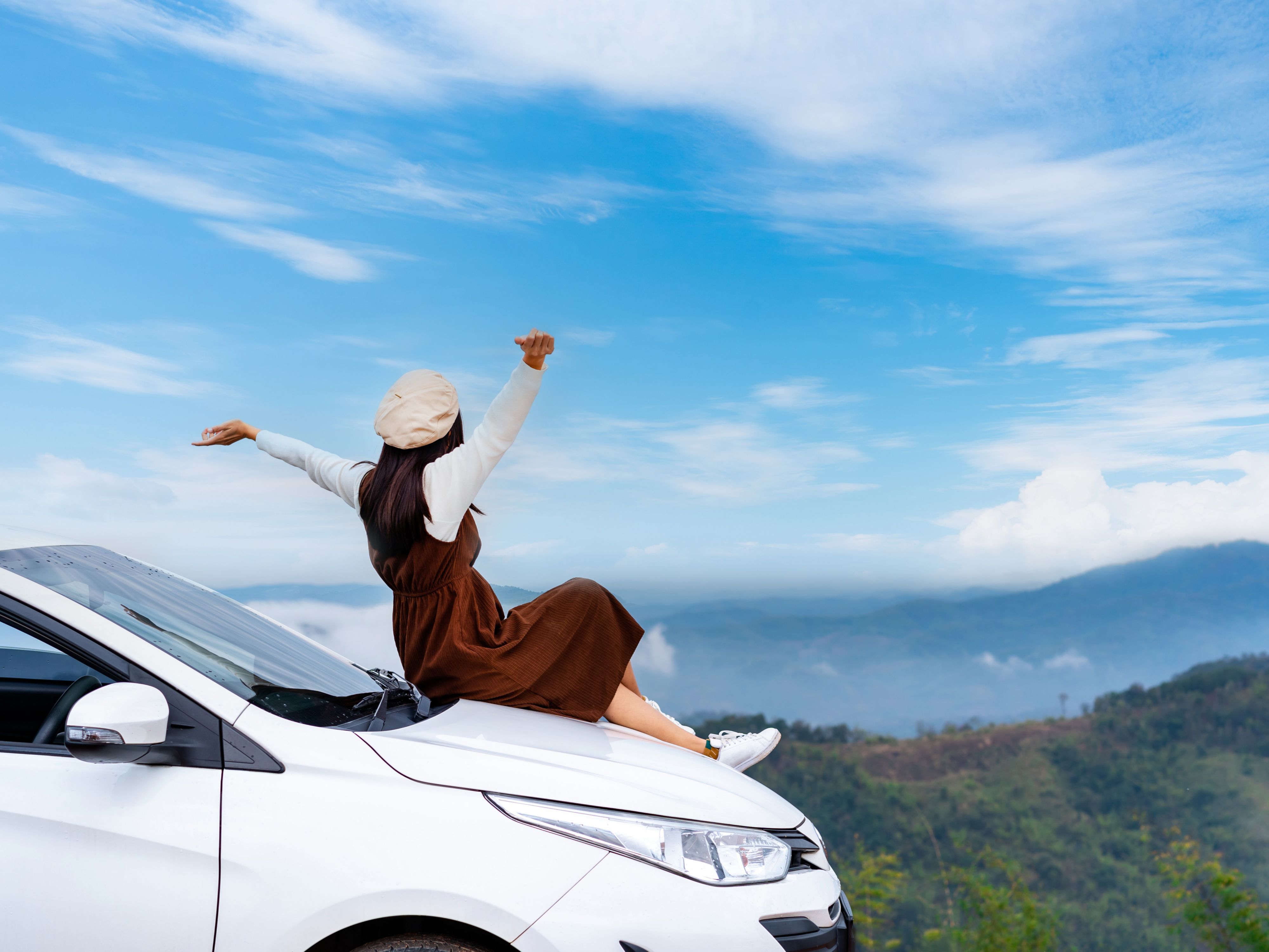 Woman on car looking out to mountains