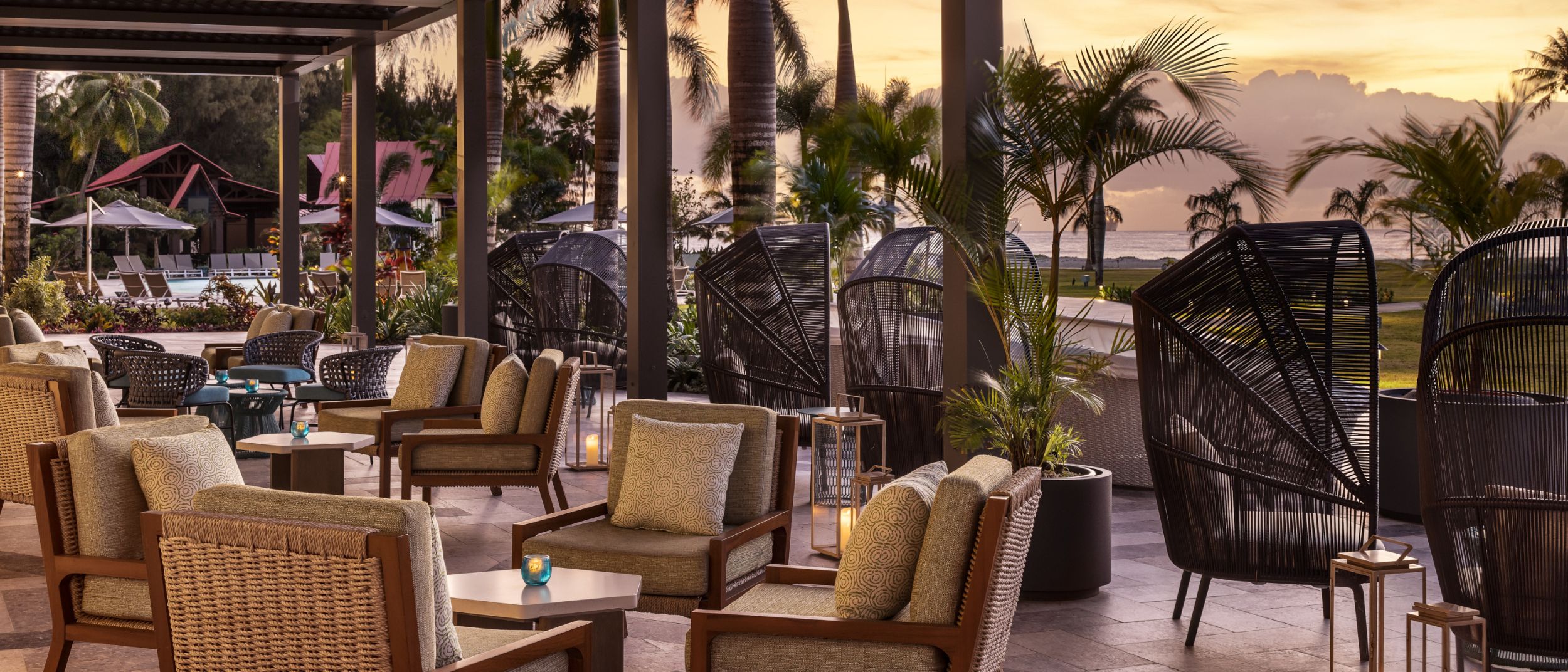 An open-air patio with seating overlooks the resort at dusk.