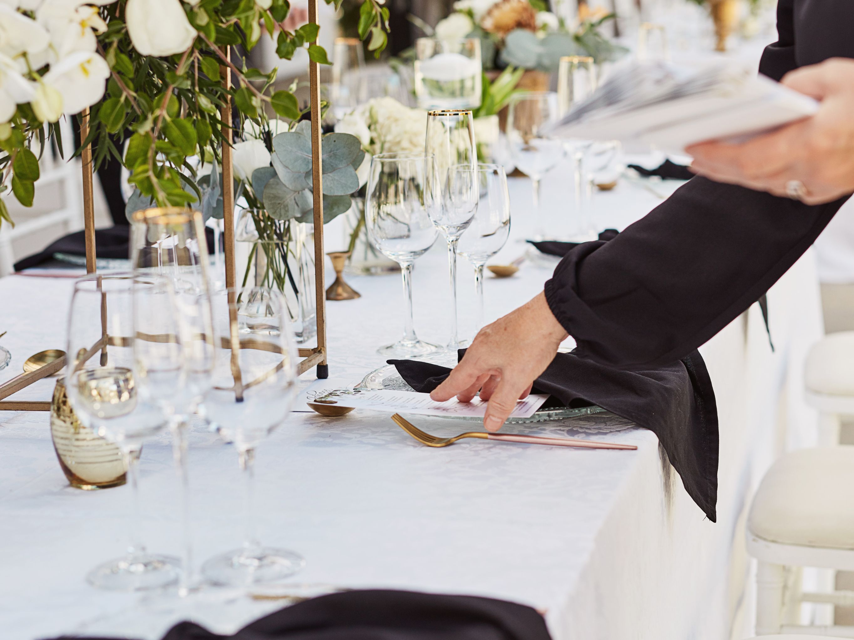 Close up of meetings director's hands setting up a table for a reception.
