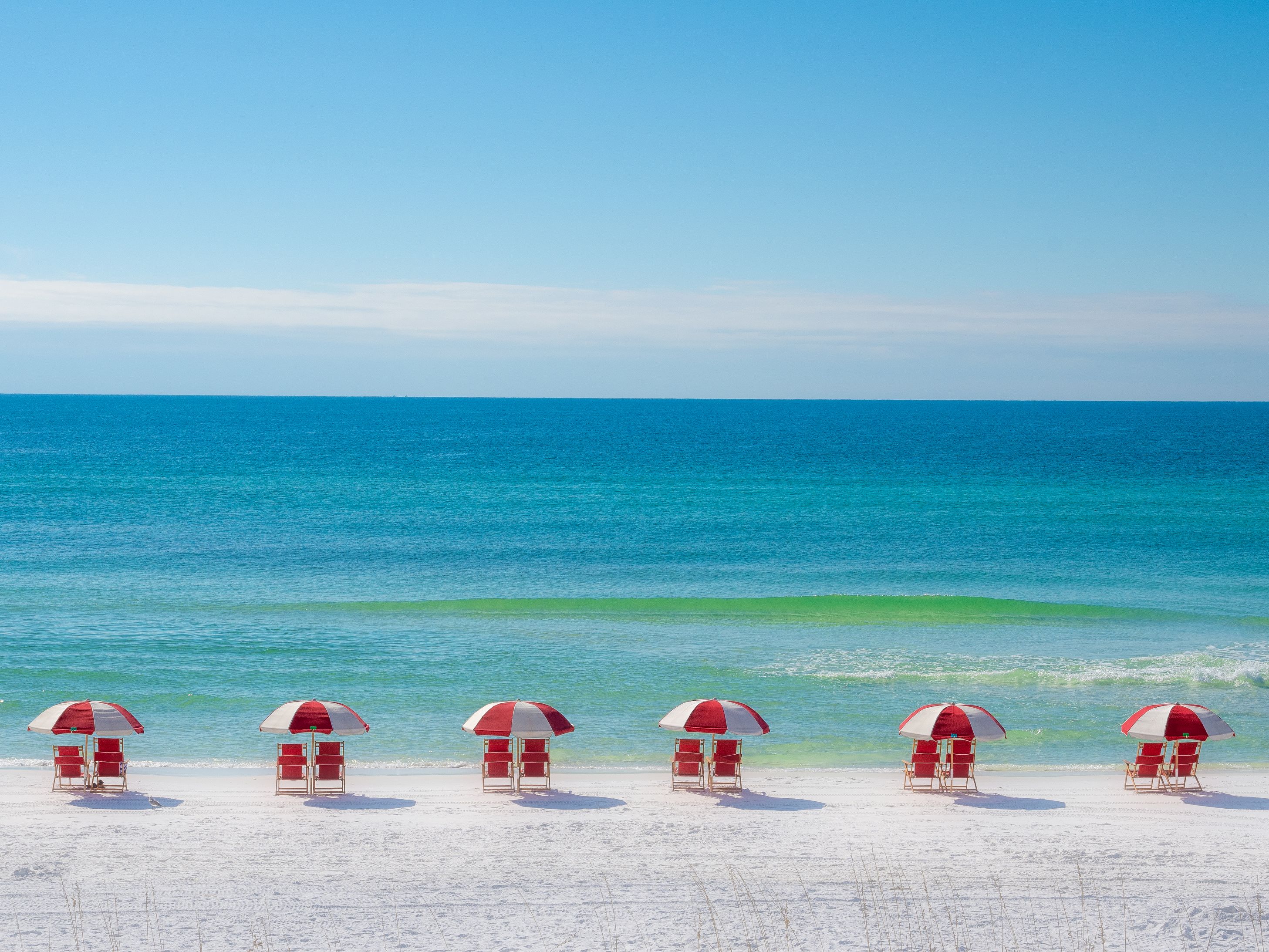 Red beach chairs and umbrellas set up on the beach.