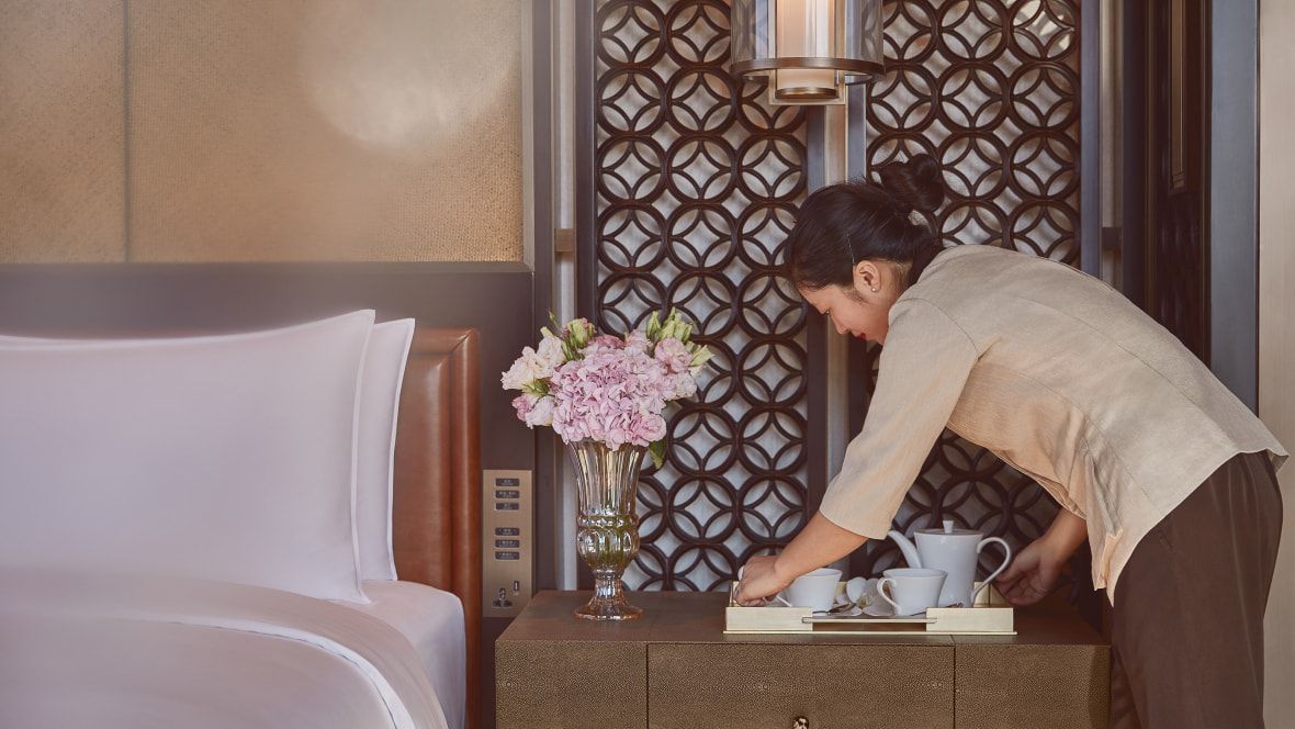 woman setting a tray with tea on a bedside table