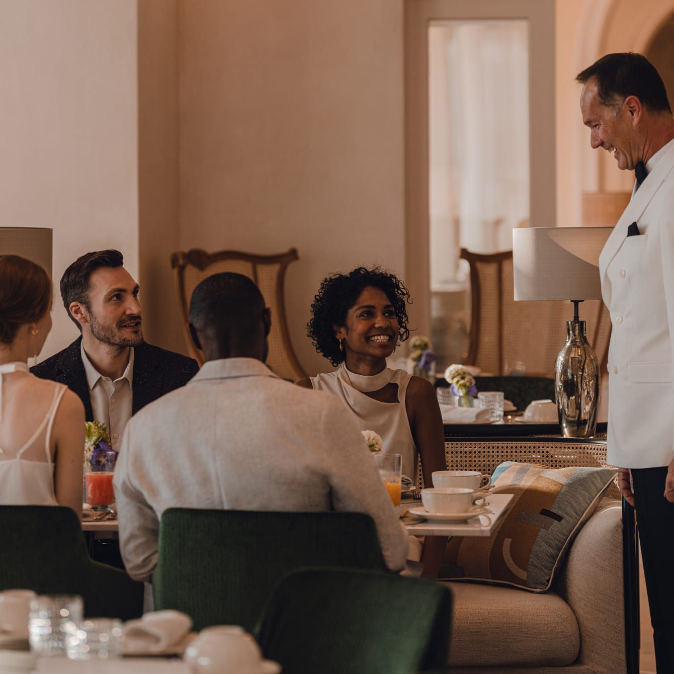 Un encantador anfitrión a la espera en una mesa de huéspedes sonrientes.