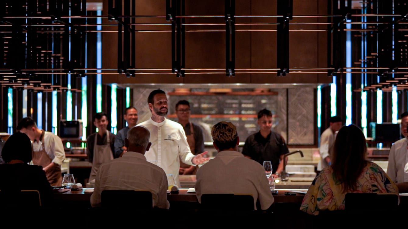 Seorang chef selebriti sedang berinteraksi dengan para tamu sebelum dia menyiapkan hidangan mereka.