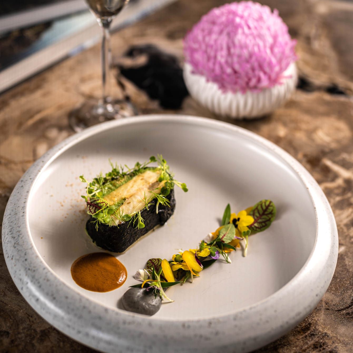 Ikan panggang yang dihidangkan dengan rapi bersama bunga dan hiasan yang bisa dimakan lainnya.