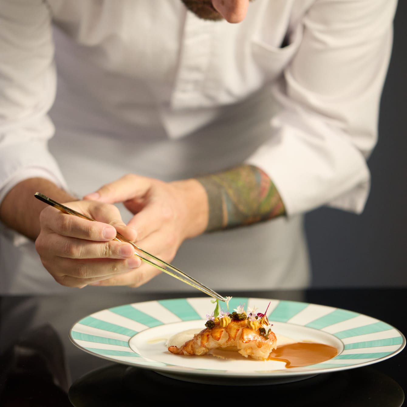 Seorang sous chef sedang memberikan sentuhan terakhir pada hidangan utama yang istimewa.