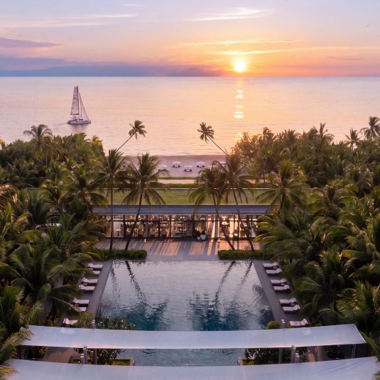 Tropical scenes unfold with pool, palms and ocean beyond