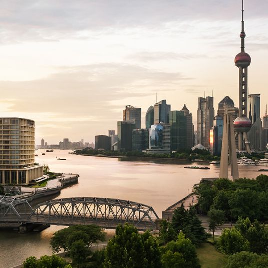 A leafy park and flowing harbor meets an ultra-modern city skyline