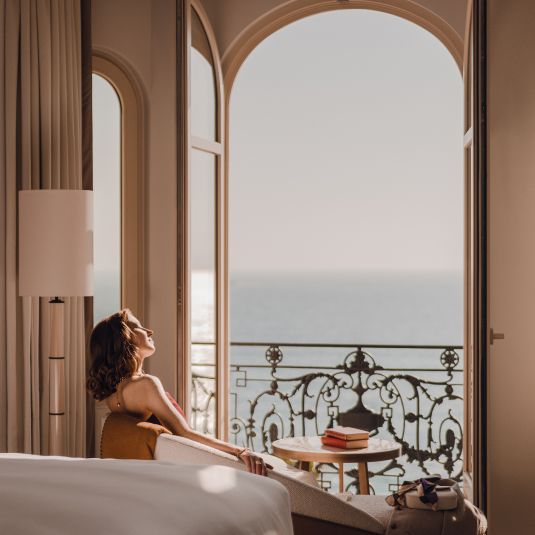 A hotel guest relaxing on her terrace balcony overlooking the French Riviera